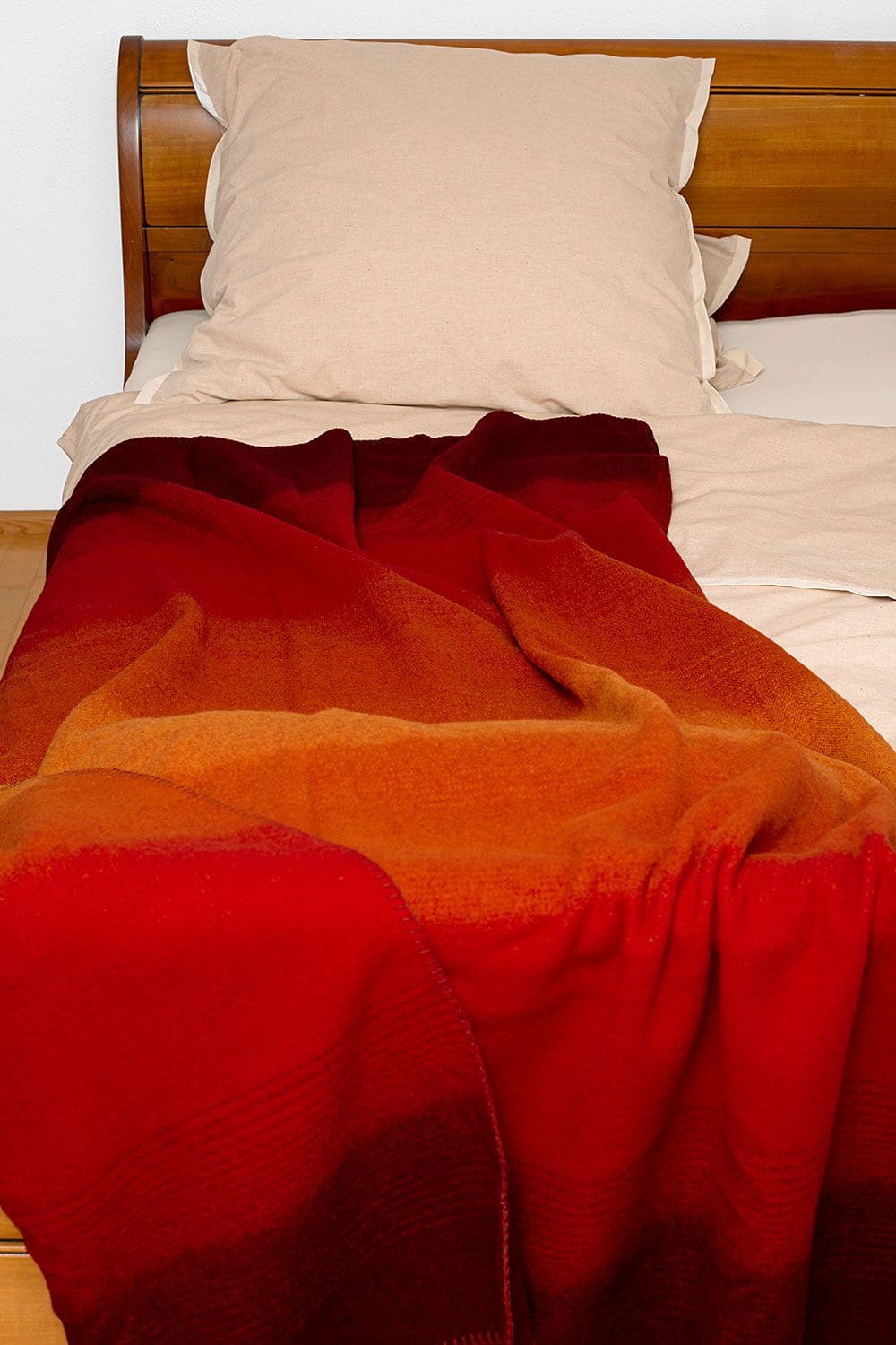 Wolldecke Herbst aus bio Wolle (kbT) liegt auf Holzbett mit hellrosa Bettwäsche