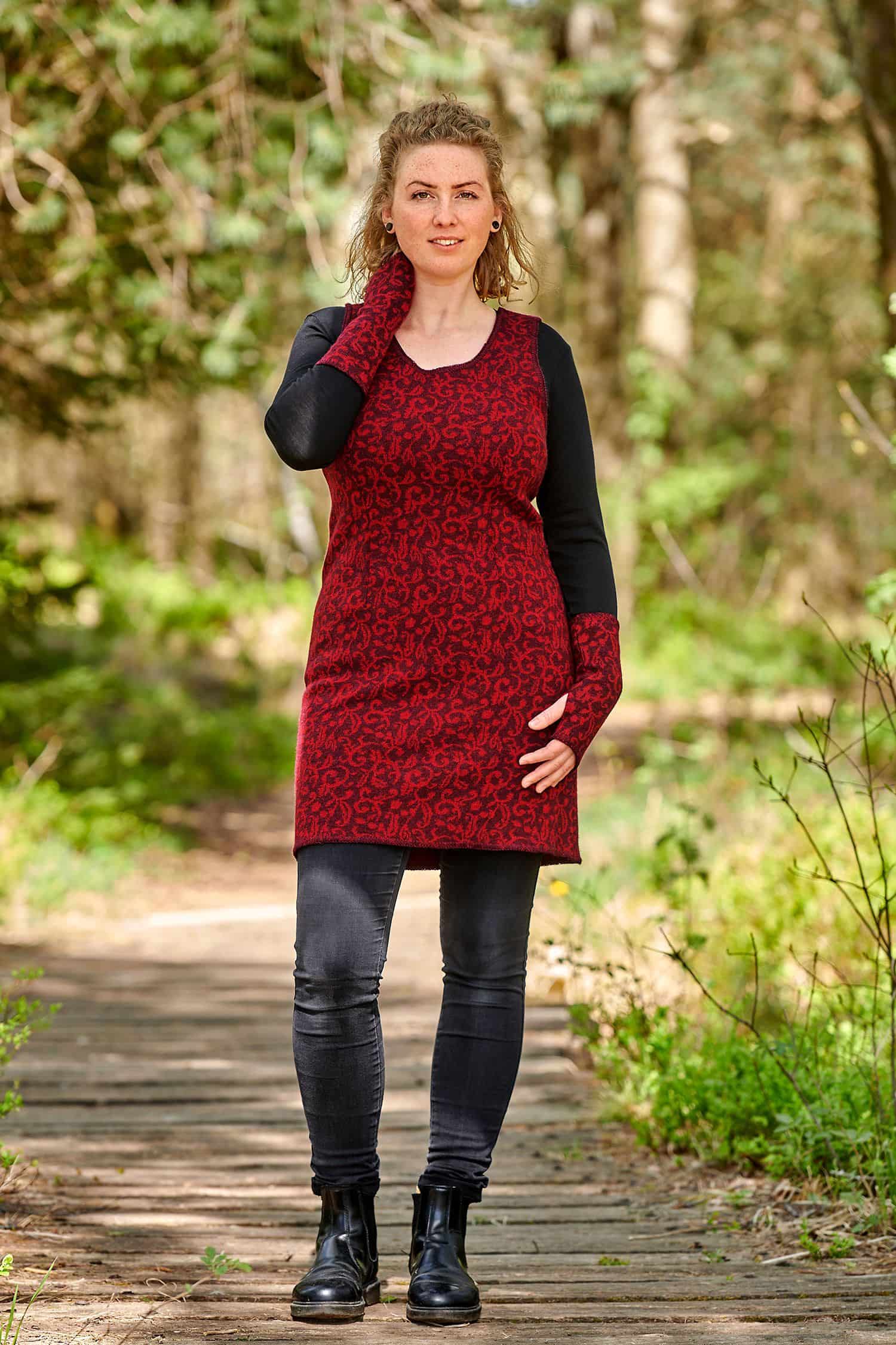 Strickkleid Ranke Frau trägt rot schwarz gemustertes Rankenstrickkleid aus bio Wolle (kbT) mit schwarzer Kleidung und Armstulpen