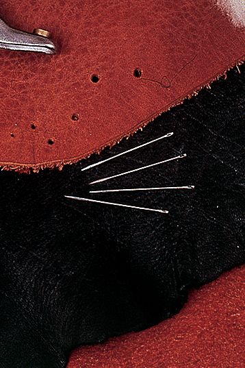 Ledernadel Ledernadeln aus Metall auf rotem Leder