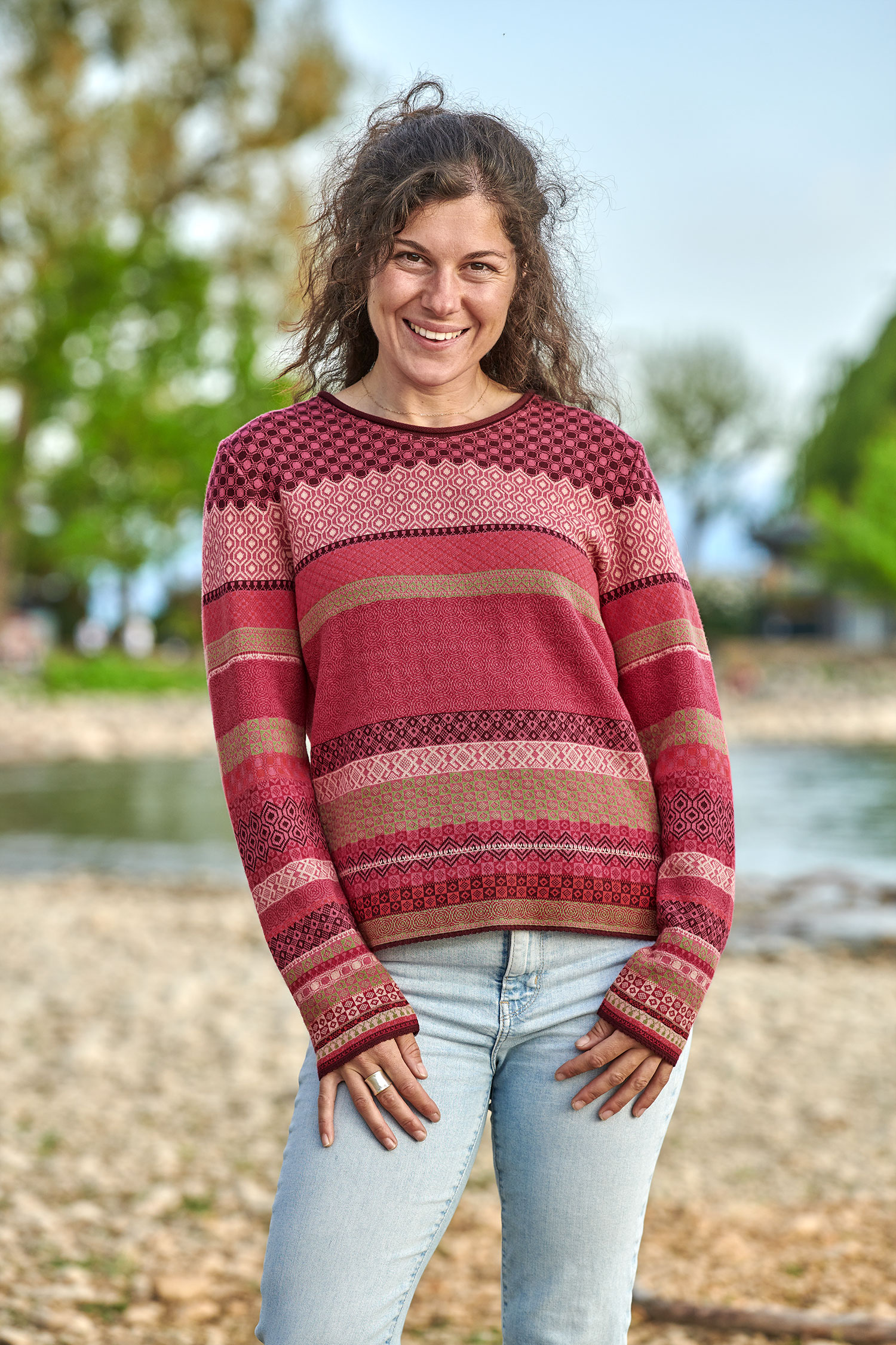 Frau trägt eine Jeans und einen Strickpullover mit Muster in beere und pink aus bio Baumwolle (kbA)