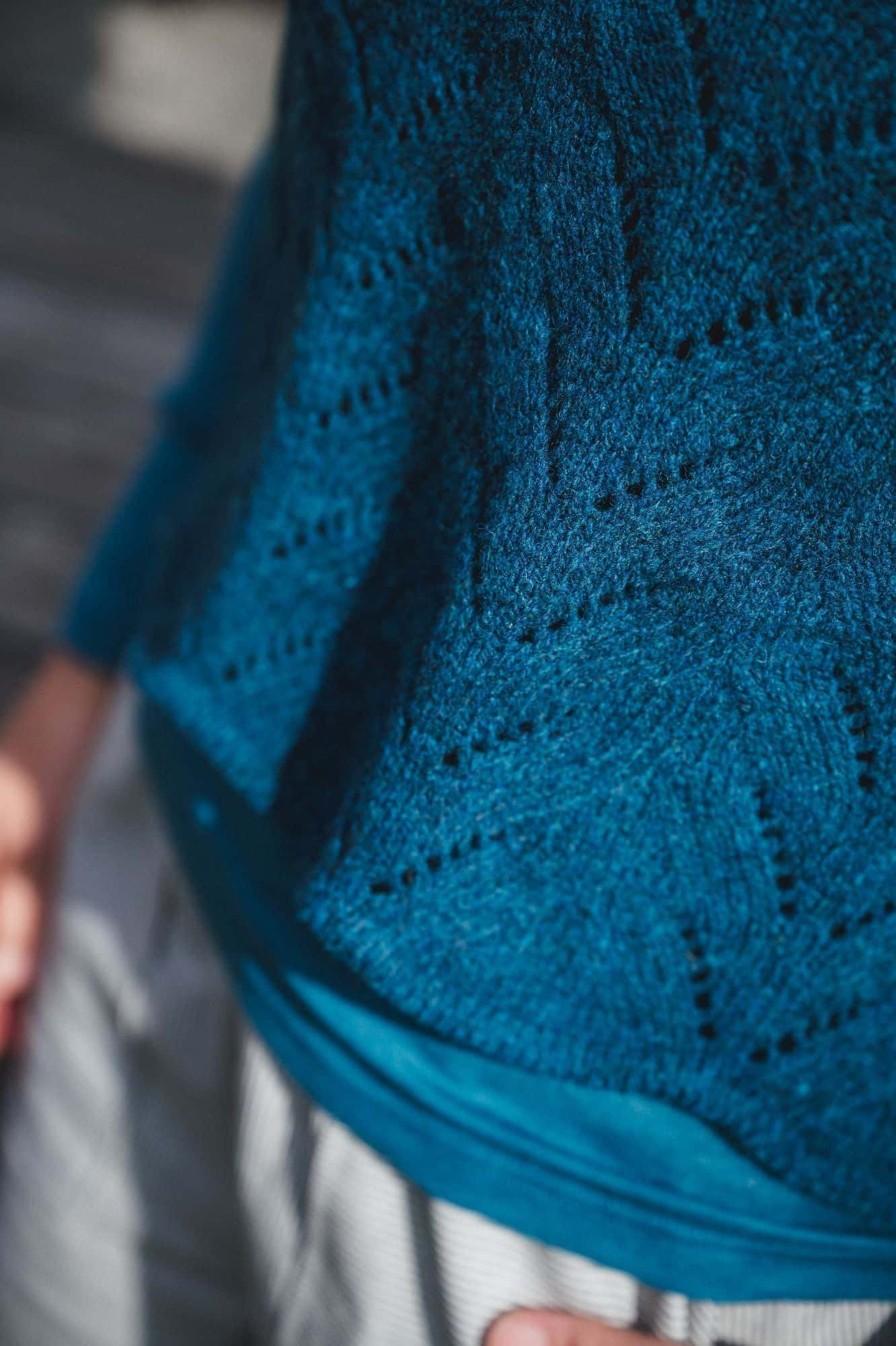 Nahaufnahme von türkisblauem Strickpullunder mit Ajourmuster vom Finkhof aus Bio-Wolle