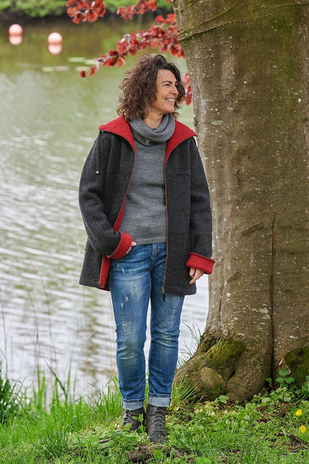 Frau mit grauem Pulli und Schal trägt dunkelgraue Jacke mit roter Innenseite aus bio Wolle (kbT) vom Finkhof
