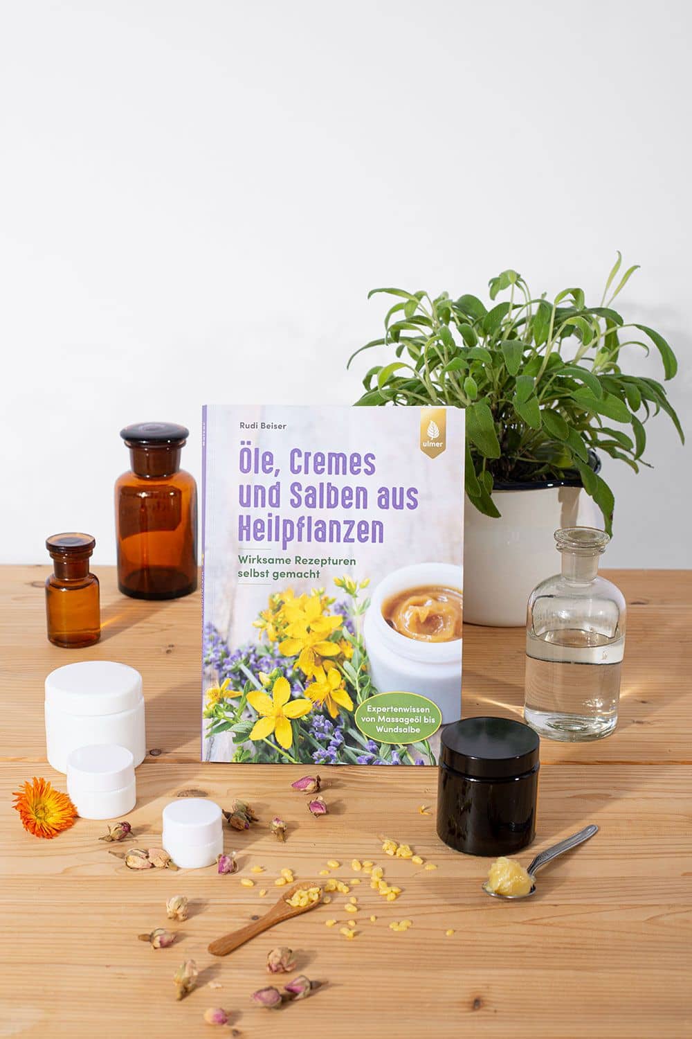 Öle, Cremes und Salben aus Heilpflanzen Buch ,,Öle, Cremes und Salben aus Heilpflanzen" auf Stimmungsbild mit Tiegeln, Fläschchen und Kräutern