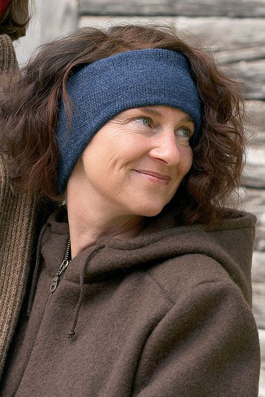 Frau mit brauner Weste trägt warmes marineblaues Stirnband vom Finkhof aus bio Wolle (kbT)