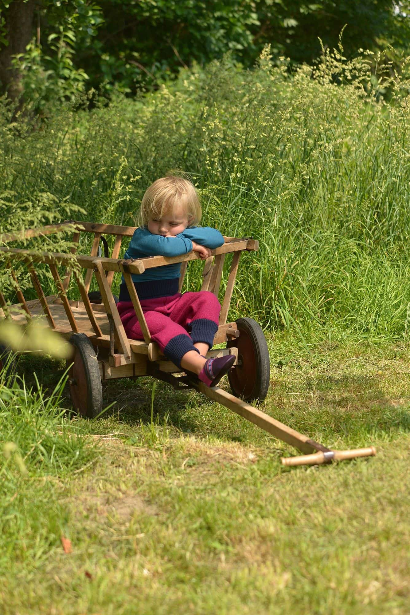 Kind sitzt in Leiterwagen und trägt lila pinke Lederpatschen aus Rindsleder vom Finkhof