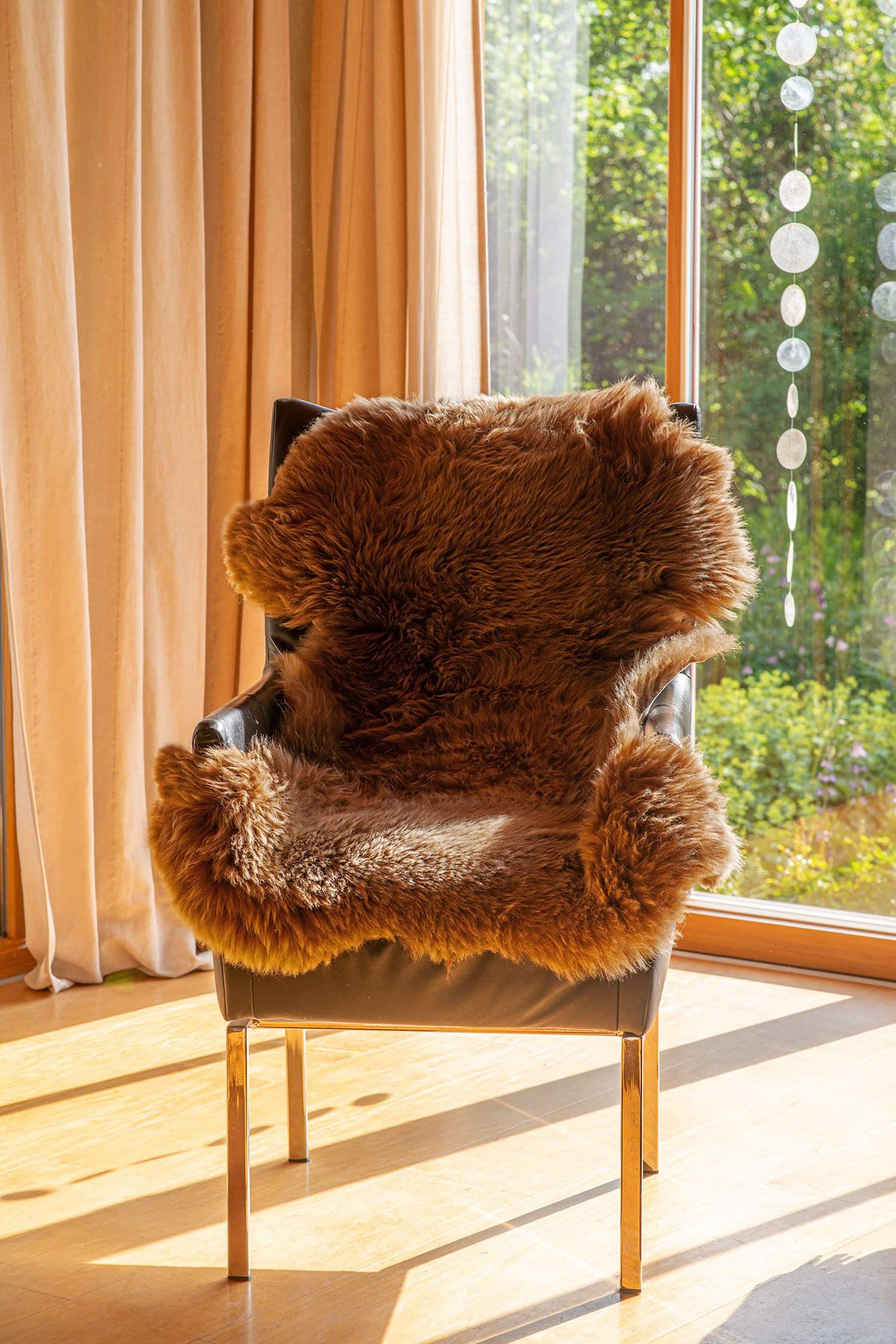 braunes pflanzlich gegerbtes Schaffell vom Finkhof auf Stuhl vor lichtdurchflutetem Fenster