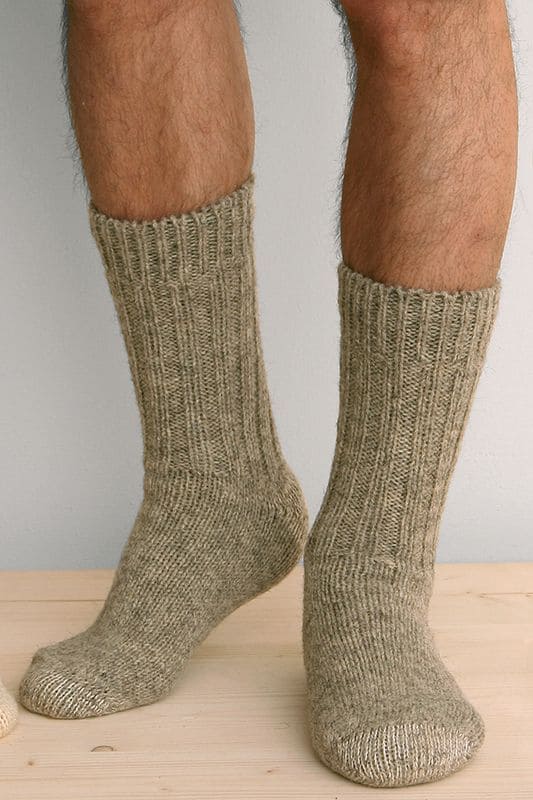 Person trägt graue dicke Finkhof Socken aus bio Wolle (kbT) auf Holzboden