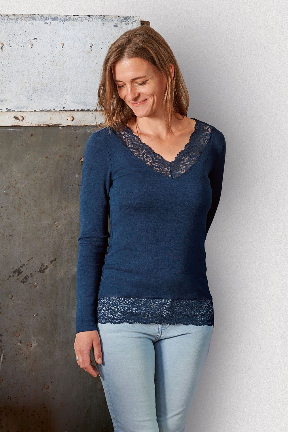 Frau trägt marineblaues Spitzenshirt aus bio Wolle (kbT) und Seide mit V Ausschnitt