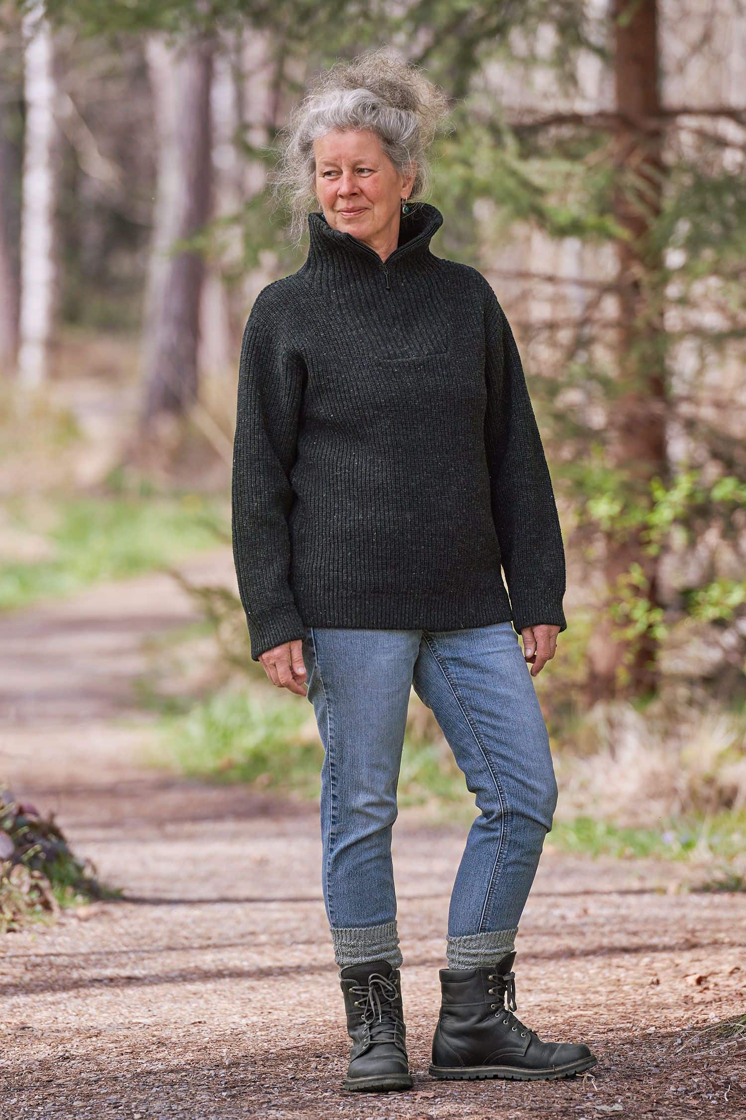 Frau mit Jeans steht im Wald und trägt anthraziten Finkhof Troyer mit Zipper aus bio Wolle (kbT)