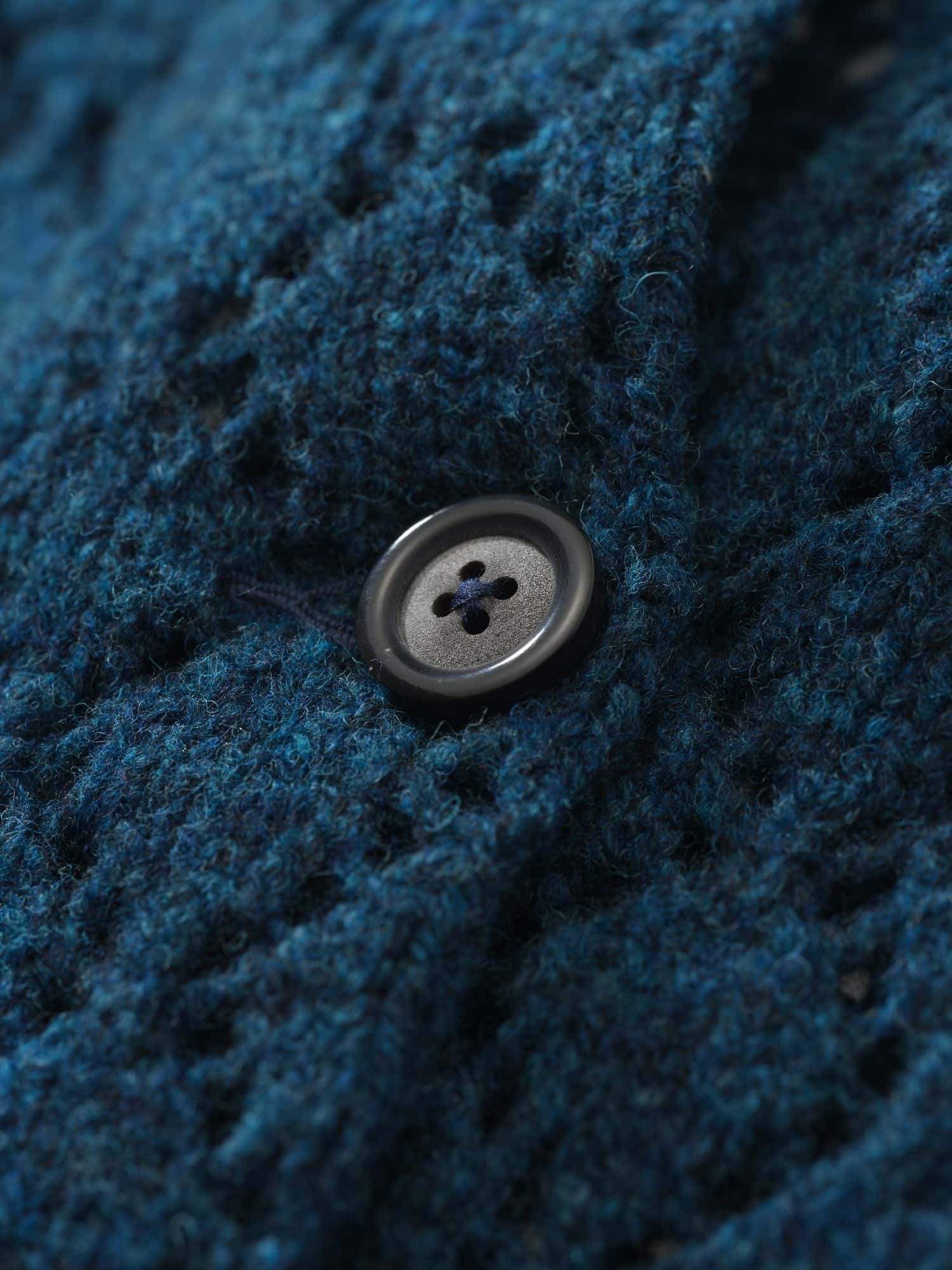 Detailaufnahme von einem Knopf der blauen Strickjacke aus Bio-Wolle vom Finkhof