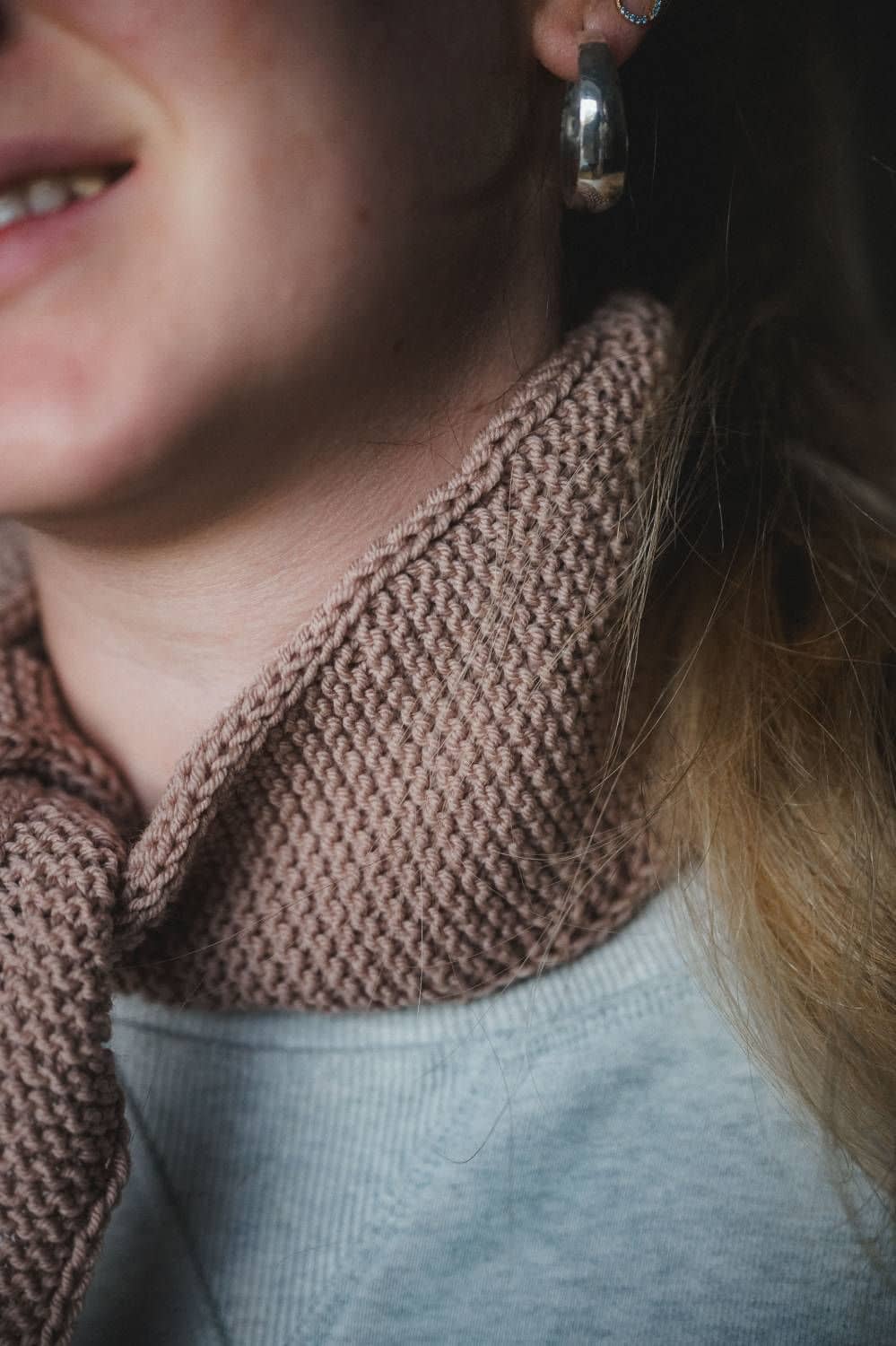 Bildausschnitt von Frau mit großem silberfarbenem Ohrring, und rosafarbenem gestrickten Halstuch aus einer Wolle vom Finkhof