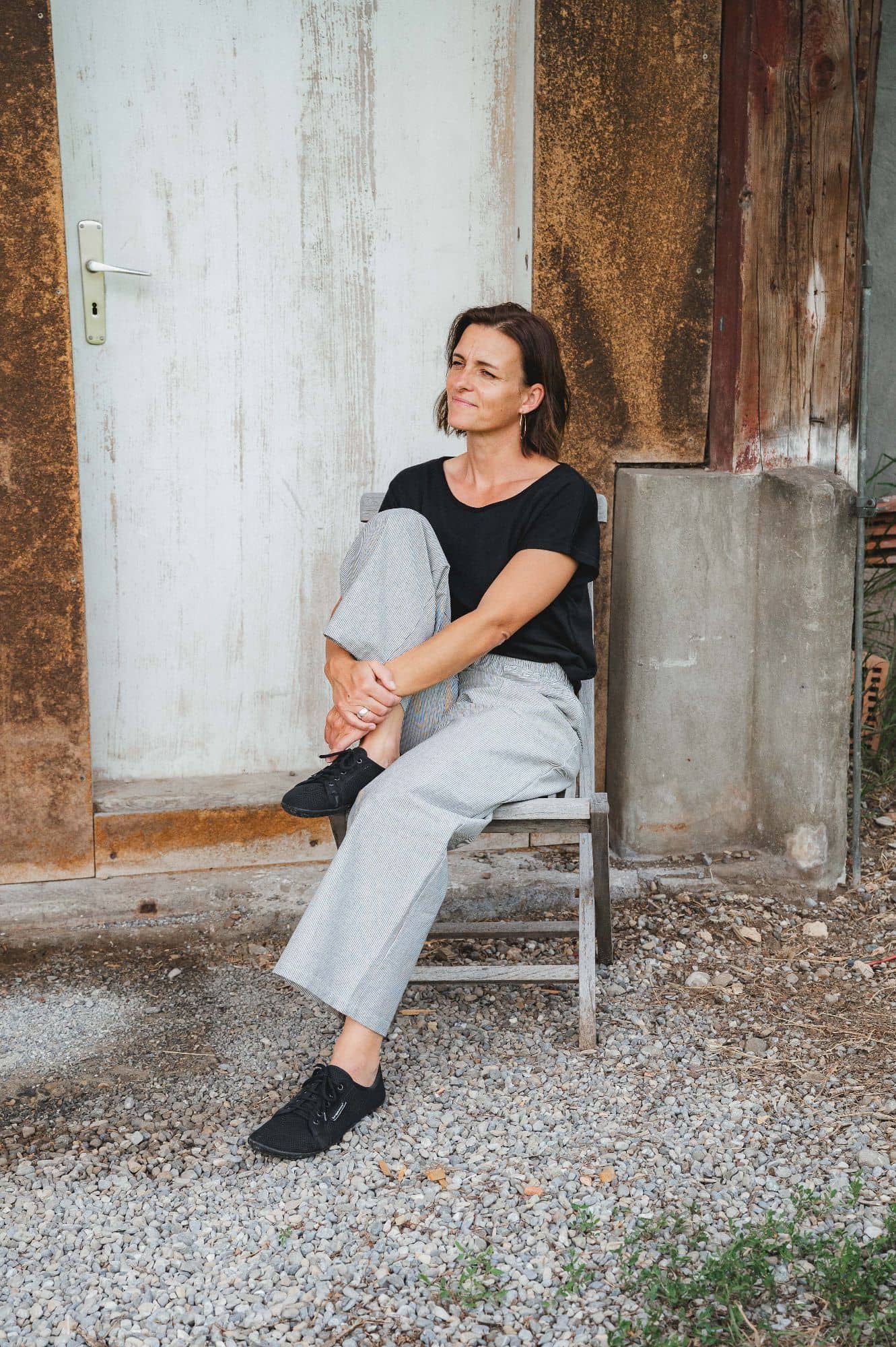 Frau sitzt auf Stuhl und trägt eine Stoffhose aus bio Baumwolle (kbA) vom Finkhof und ein schwarzes Shirt