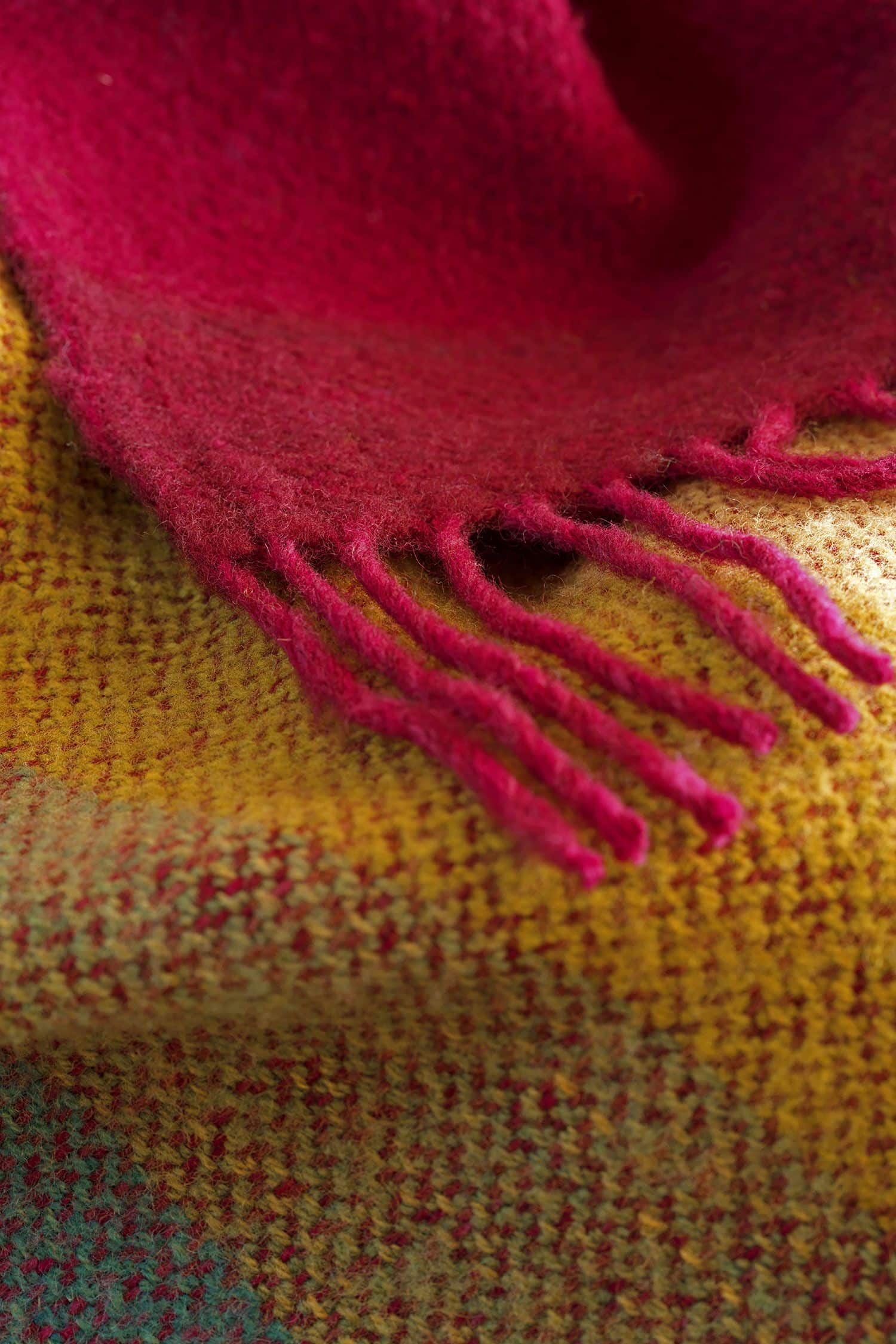 Detailaufnahme der pinken Fransen der regenbogenfarbenen Wolldecke aus bio Wolle (kbT) vom Finkhof