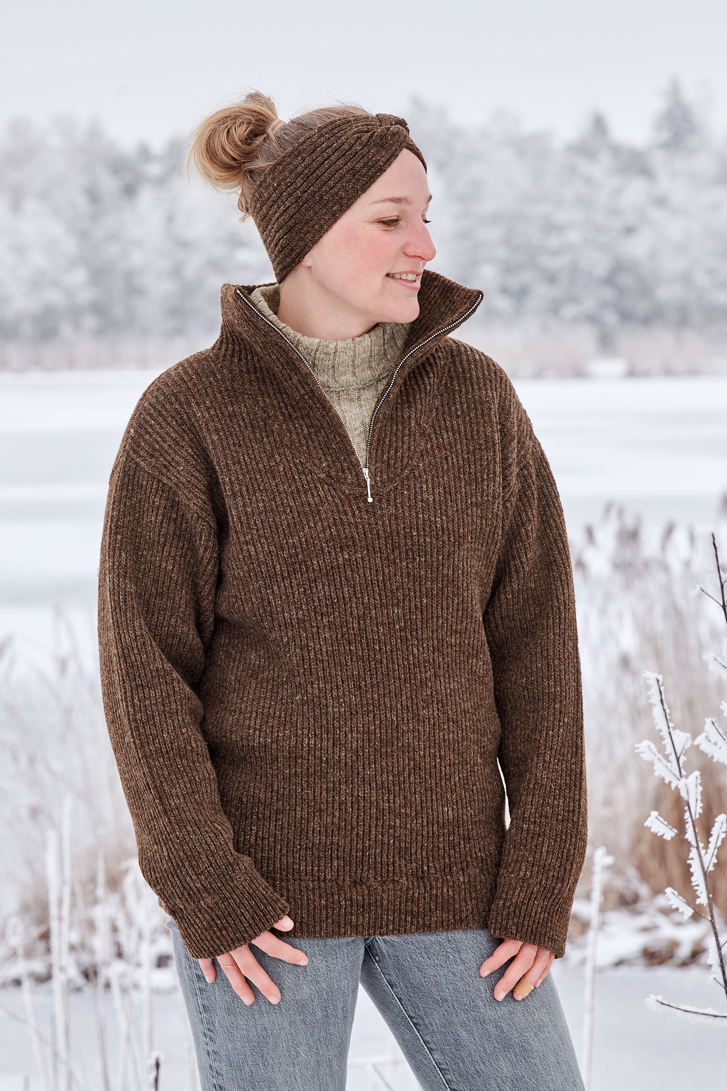 Frau in Schneelandschaft trägt braunen Finkhof Troyer aus bio Wolle (kbT) und ein braunes Stirnband mit Twist