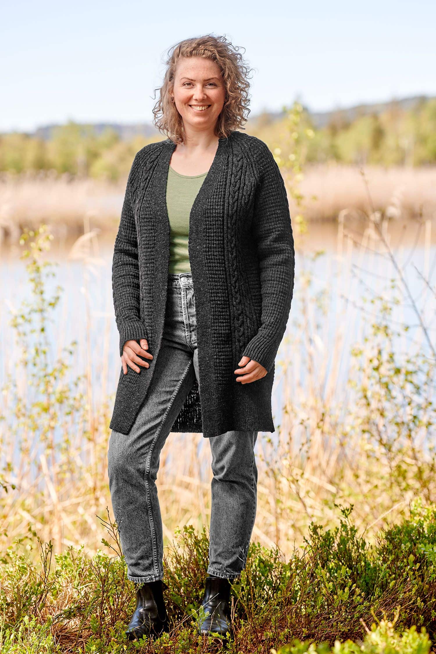 Finkhof-Zopfmuster-Cardigan gefärbt Frau trägt eine Jeans, grünes Shirt und einen dunkelgrauen Cardigan mit Zopfmuster aus bio Wolle (kbT) vom Finkhof