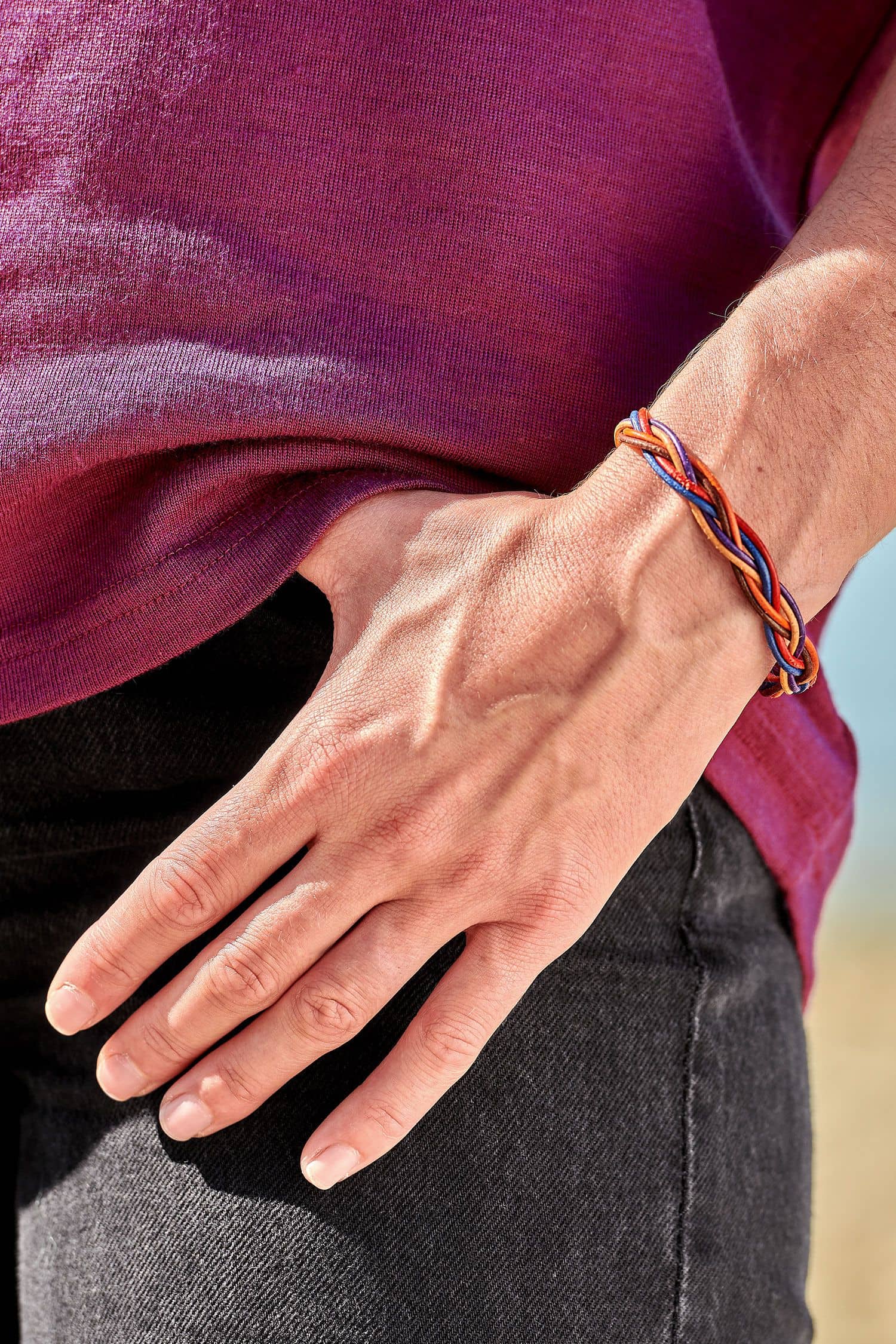 Frau mit beerefarbenem Shirt trägt geflochtenes Lederarmband aus Rinds- und Ziegenleder mit silberfarbenem Verschluss