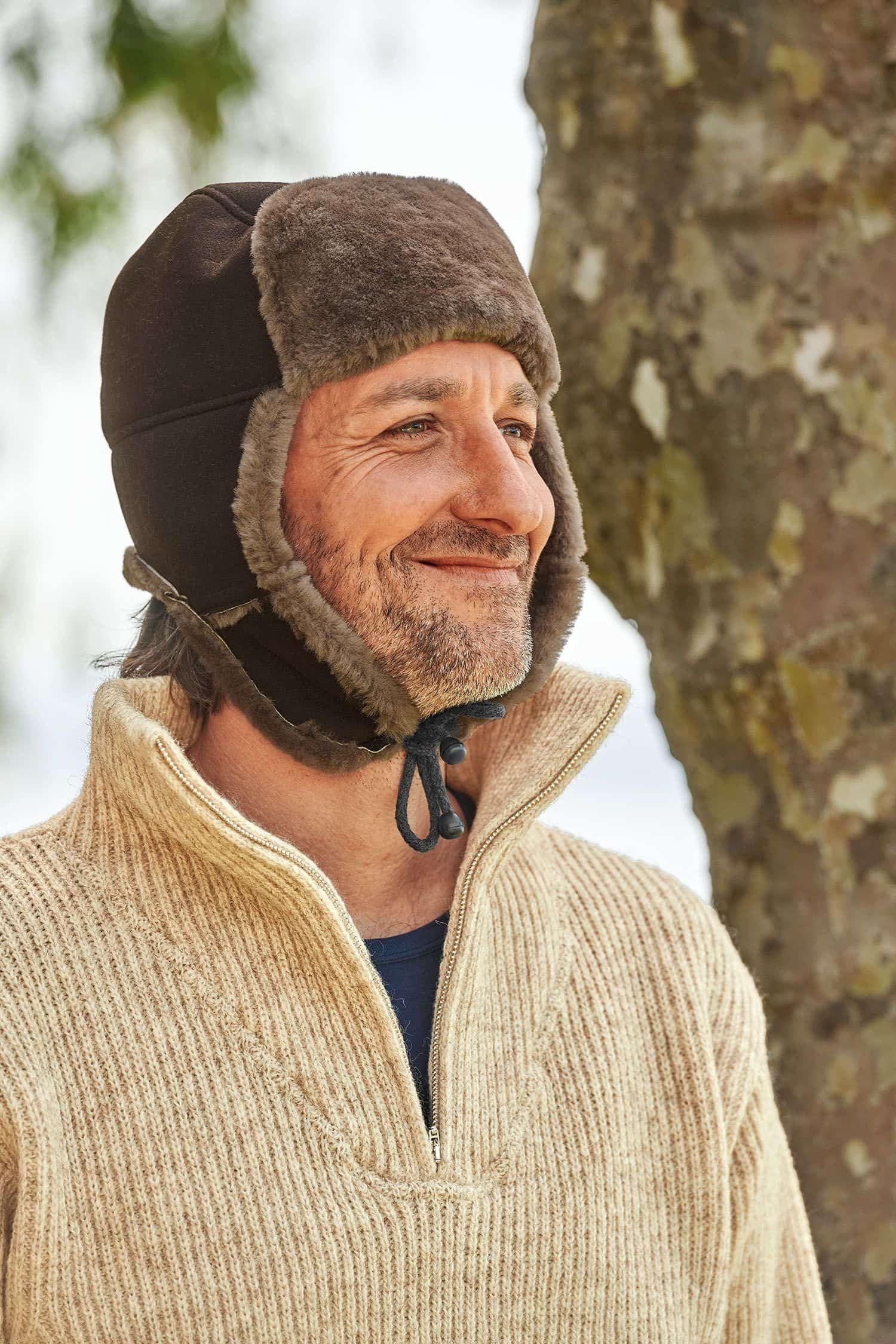 Mann mit Finkhof Troyer trägt eine braune Fellmütze aus Schaffell vom Finkhof