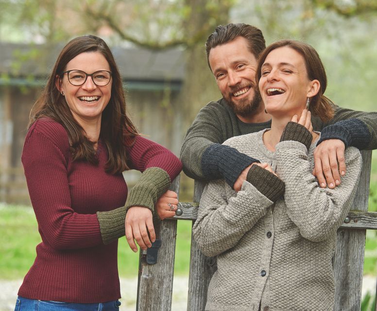Drei fröhliche Menschen tragen Finkhof Naturmode aus Wolle