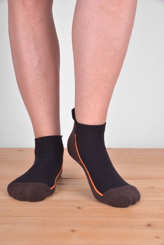 kurze braun/orange Sportsocken aus bio Baumwolle (kbA), Polyamid und Elasthan, getragen auf Holzboden von vorne