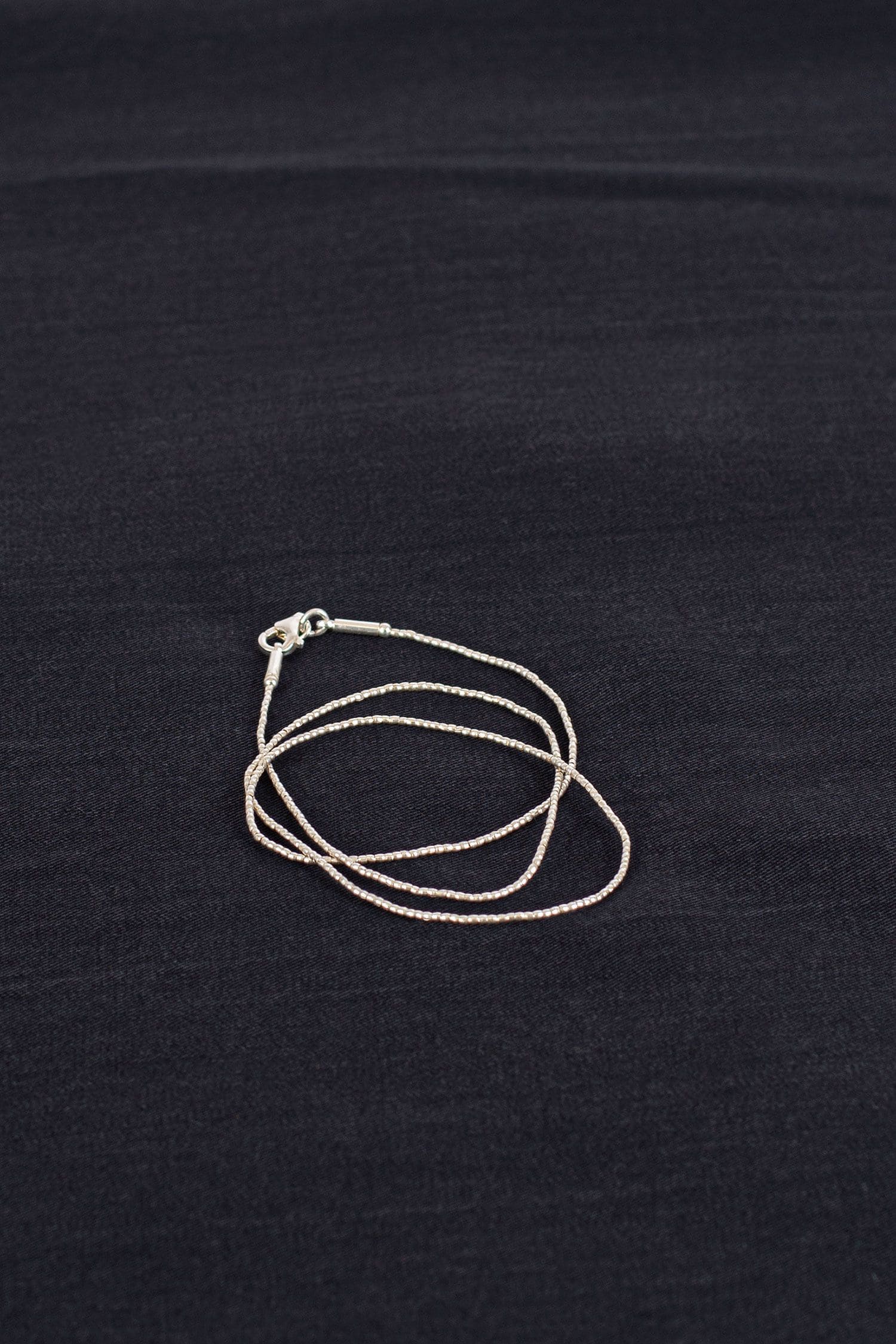 feine silberne Halskette auf schwarzem Untergrund