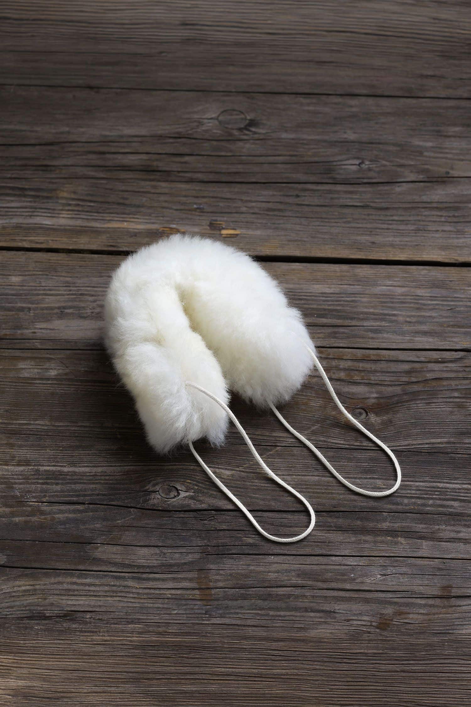 weißer Türstopper für die Türklinke aus pflanzlich gegerbtem Schaffell vom Finkhof, auf braunem Holzboden