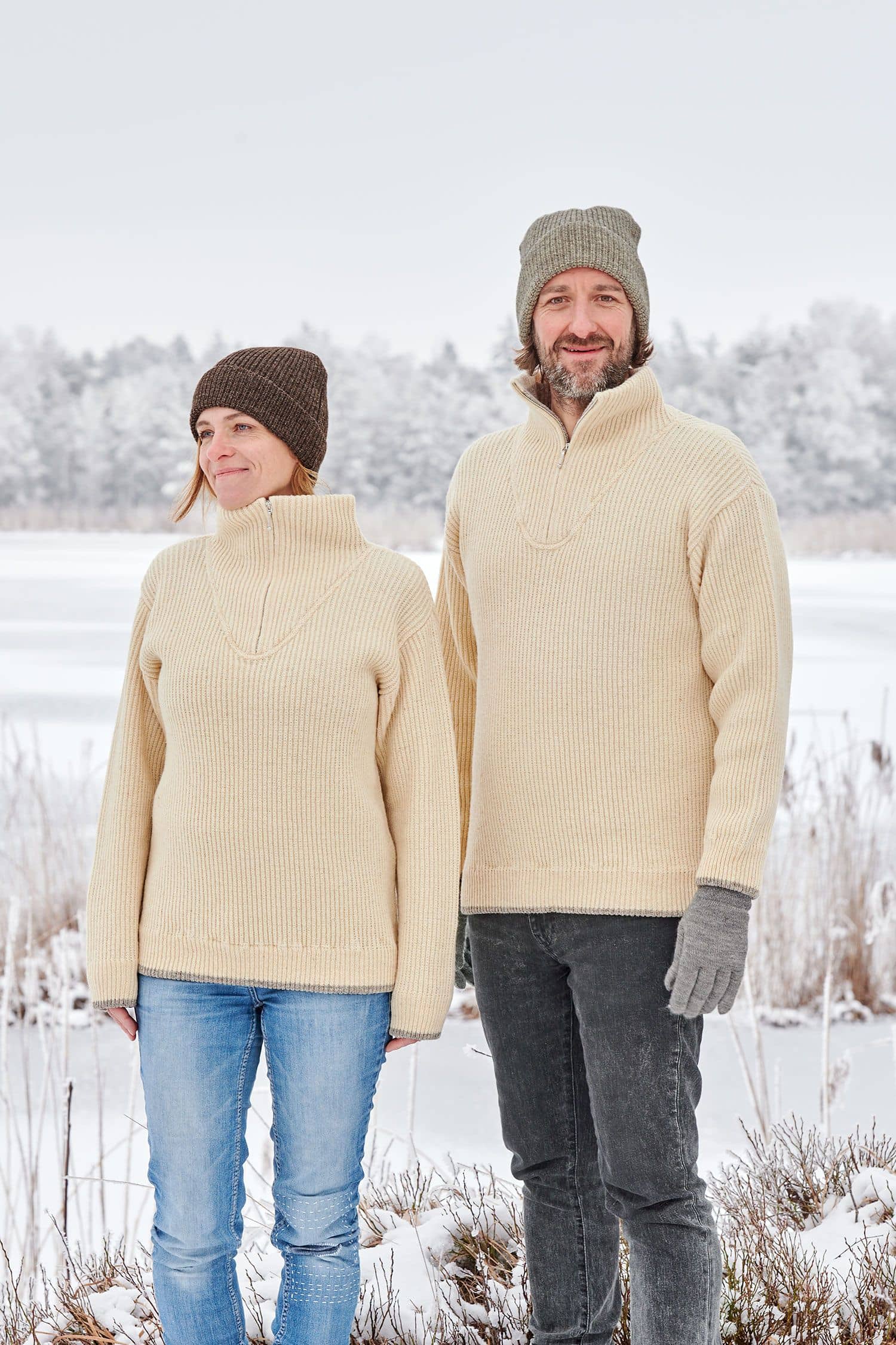 Frau und Mann mit Mützen und naturweißen Finkhof Troyern aus bio Wolle (kbT) in Schneelandschaft