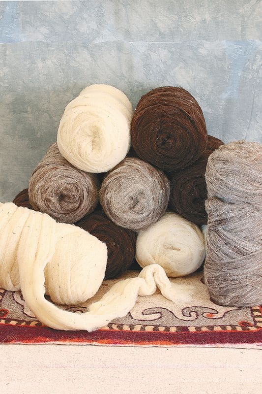 Kardierte Wolle 1 kg kardierte Wolle aus bio Wolle (kbT) vom Finkhof in verschiedenen Farben aufgerollt gestapelt auf rotem Teppich