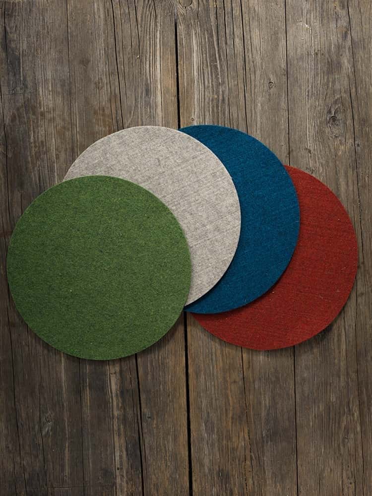 runde Finkhof Sitzauflagen in verschiedenen Farben aus bio Wolle (kbT) auf braunem Holzboden