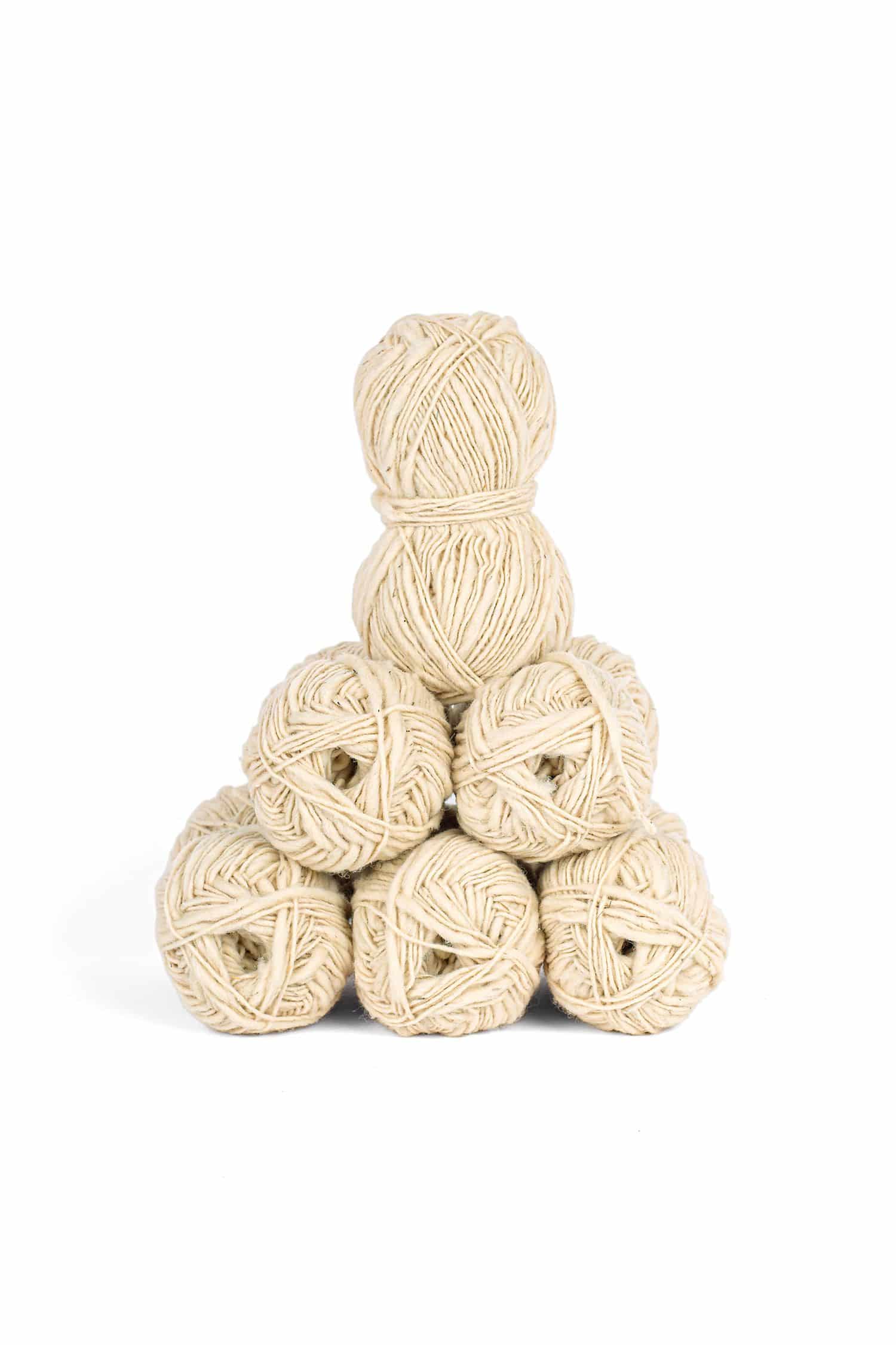naturweißes Finkhof Flammengarn aus bio Wolle (kbT) in Knäulen als Pyramide aufgestapelt
