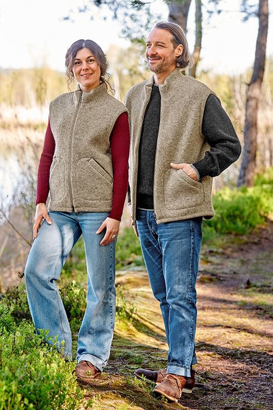 Finkhof-Wollwalkweste ungefärbt Mann und Frau tragen die graue ungefärbte Finkhof Wollwalkweste aus bio Wolle (kbT) mit unifarbigen Shirts und Jeans