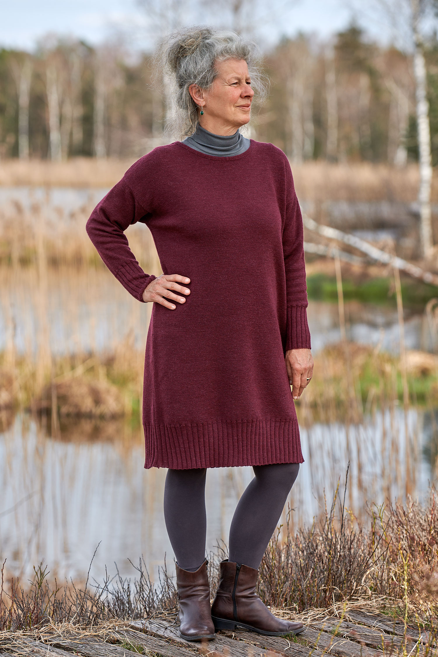 Frau trägt burgunderrotes Strickkleid aus bio Wolle (kbT) mit einen grauen Rollkragenshirt