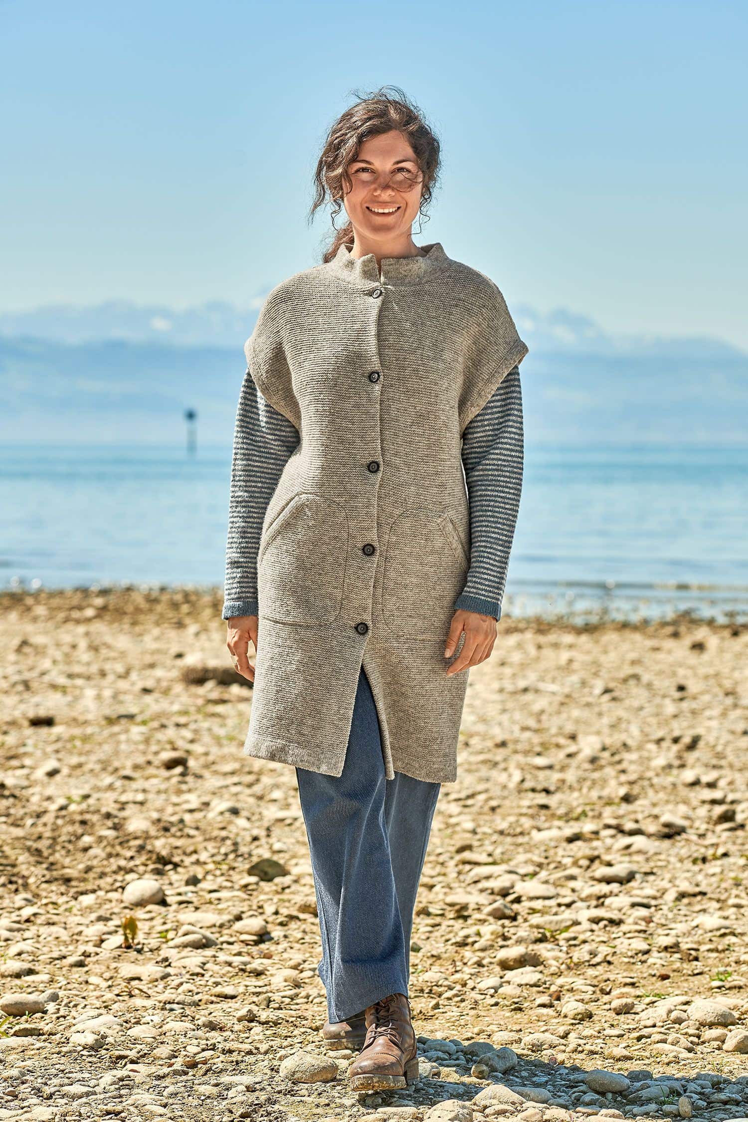 Frau trägt einen blauen Streifenpullover und eine graue lange Strickjacke vom Finkhof aus bio Merinowolle (kbT)