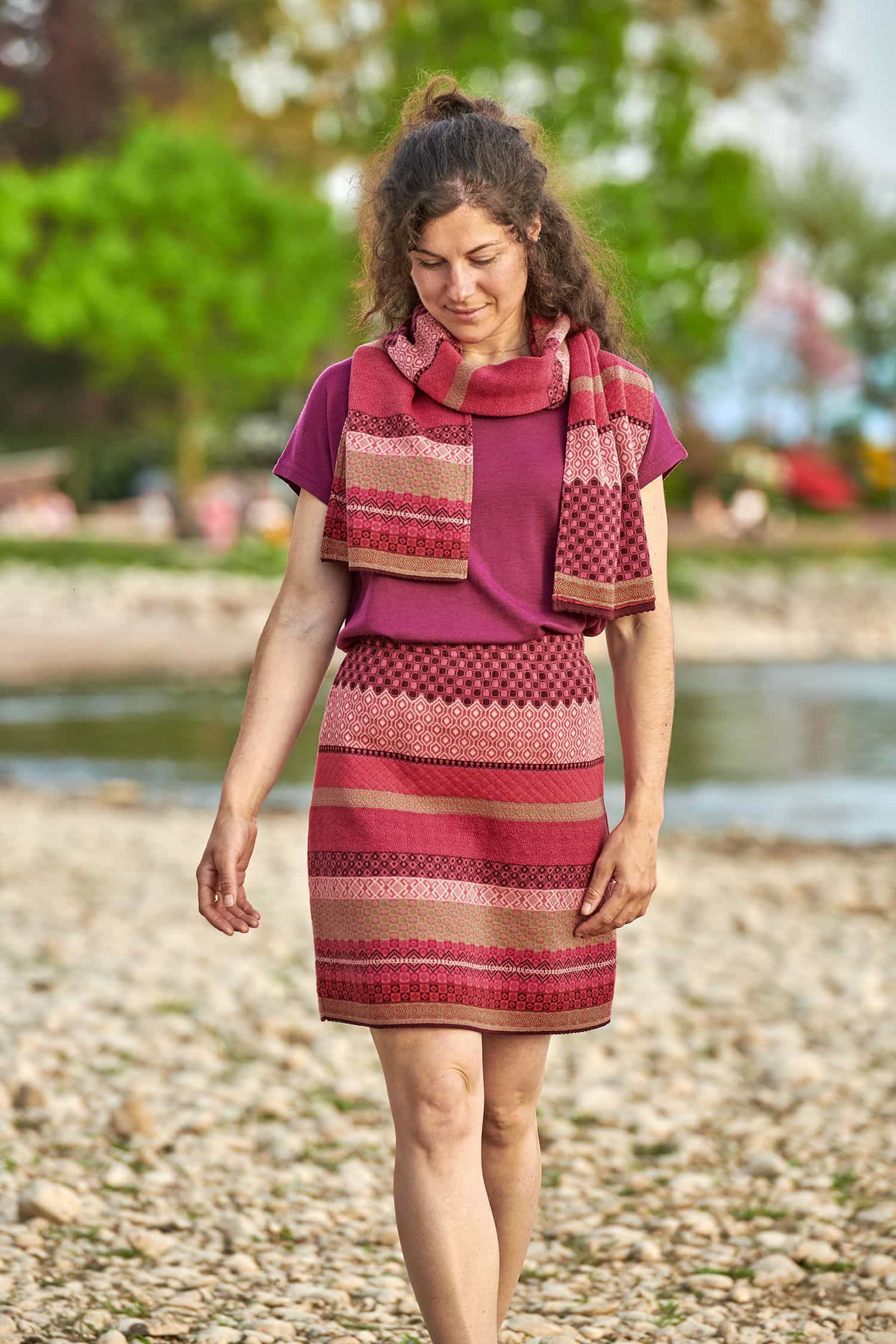 Baumwoll-Strickrock brombeer/pink Gr. M Frau trägt gemusterten Strickschal aus bio Baumwolle (kbA) in beere und pink, einen Rock und ein Shirt