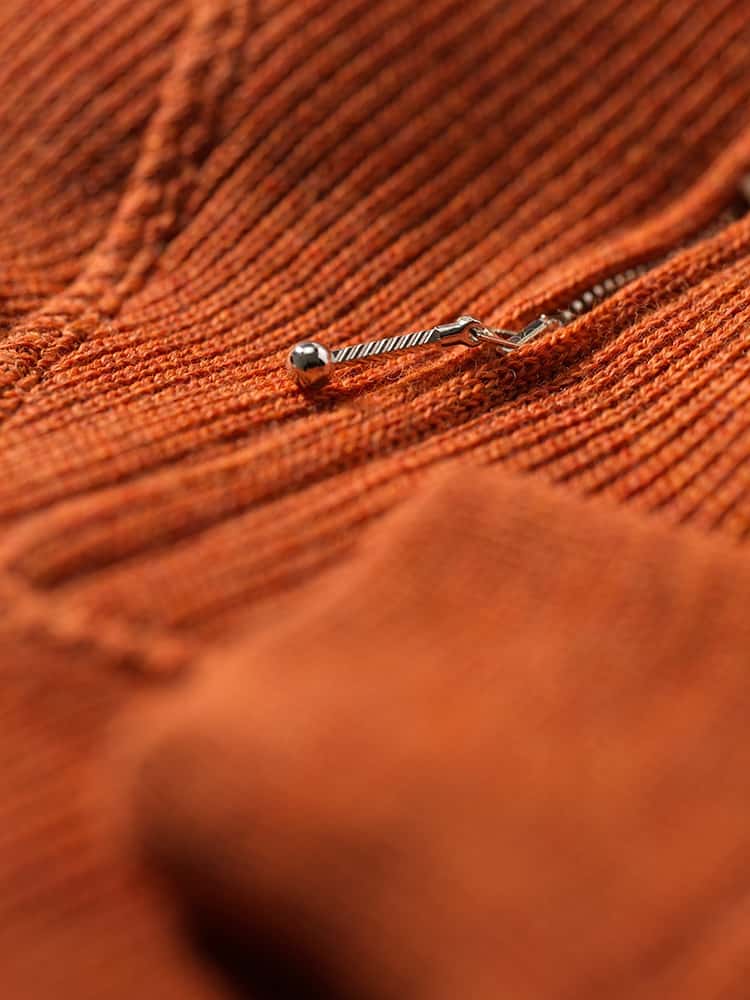 Detailaufnahme des Reißverschluss des orangen Troyer vom Finkhof aus bio Wolle (kbT)