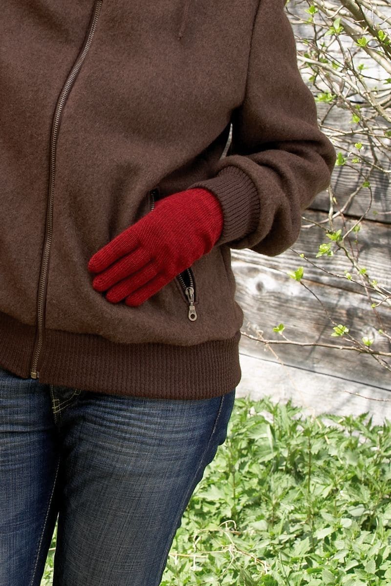 Nahaufnahme von Frau mit brauner Weste und roten Strickhandschuhe mit Fingern aus bio Wolle (kbT) vom Finkof