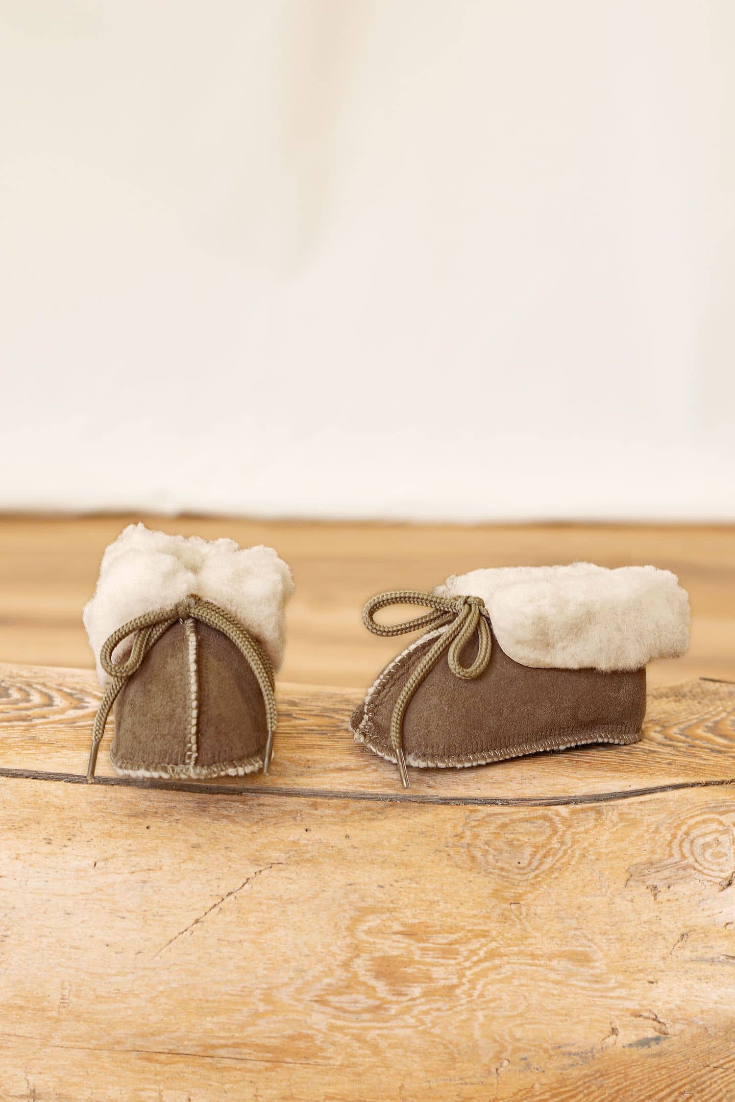 Fellschuhe für Kinder aus pflanzlich gegerbtem Schaffell stehen auf Holzboden