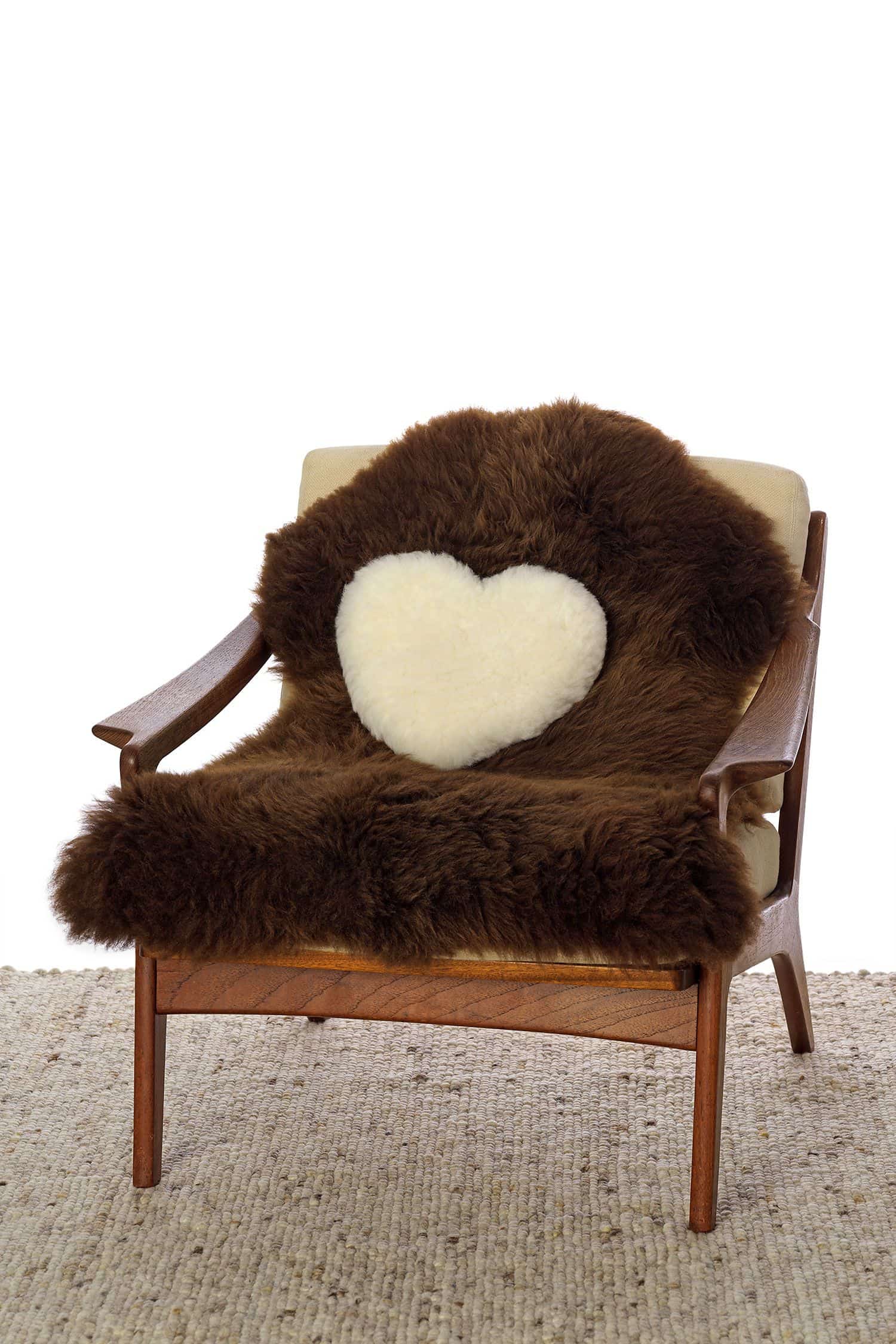 Herzkissen pflanzlich gegerbt weißes pflanzlich gegerbtes Herzkissen aus Finkhof Schaffell auf braunem Fell und Sessel