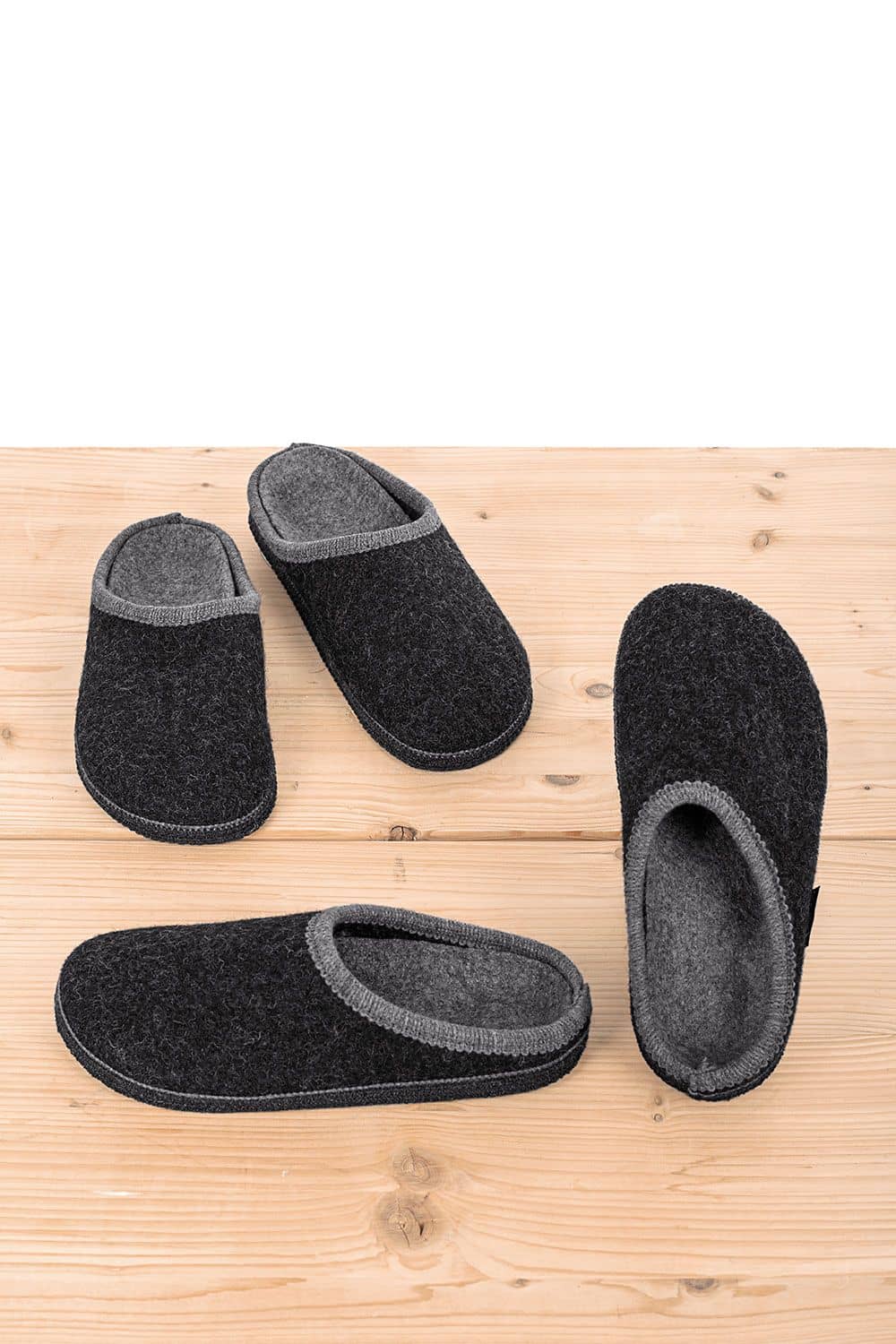 Pantoffeln mit Korkfußbett zwei Paar dunkelgraue Pantoffeln mit Korkfußbett stehen auf hellem Holzuntergrund
