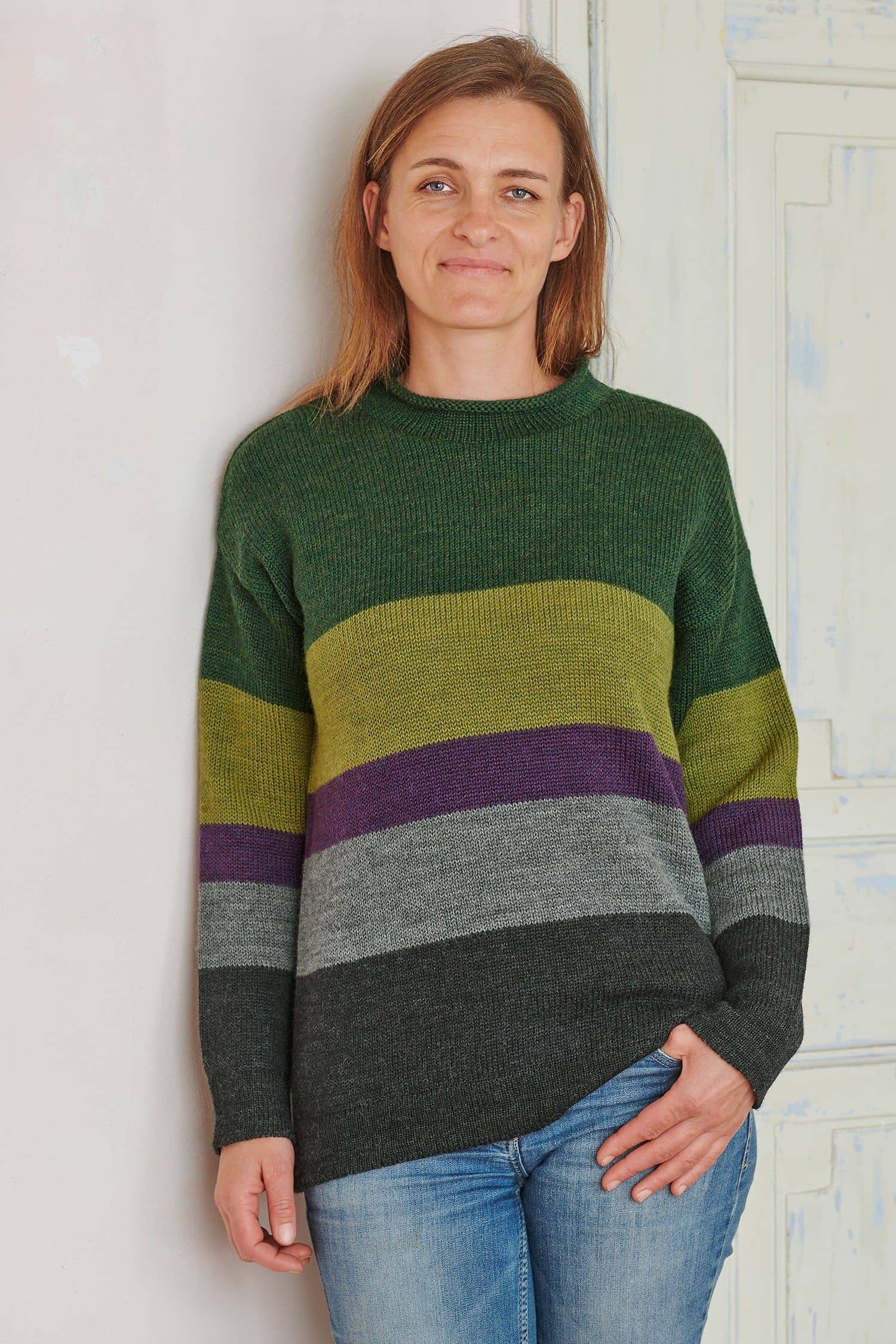 Frau trägt einen Pulli mit Blockstreifen in grün aus bio Merinowolle (kbT)
