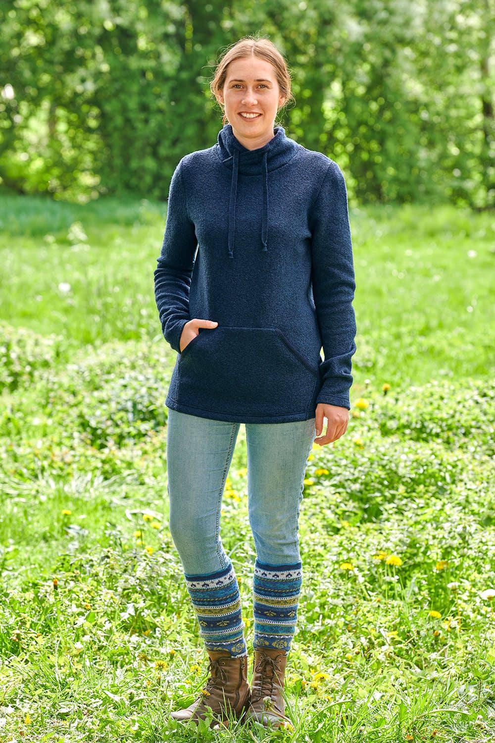 Frau steht draußen mit marineblauem Pulli aus bio Wolle (kbT) Jeans und gemusterten Beinstulpen