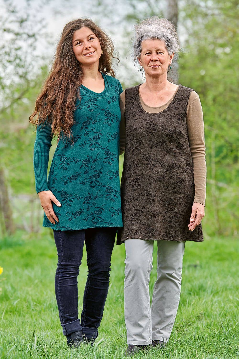Frauen in der Natur tragen türkise und braune Walktunika aus bio Wolle (kbT) mit unifarbenen Shirts und Jeans
