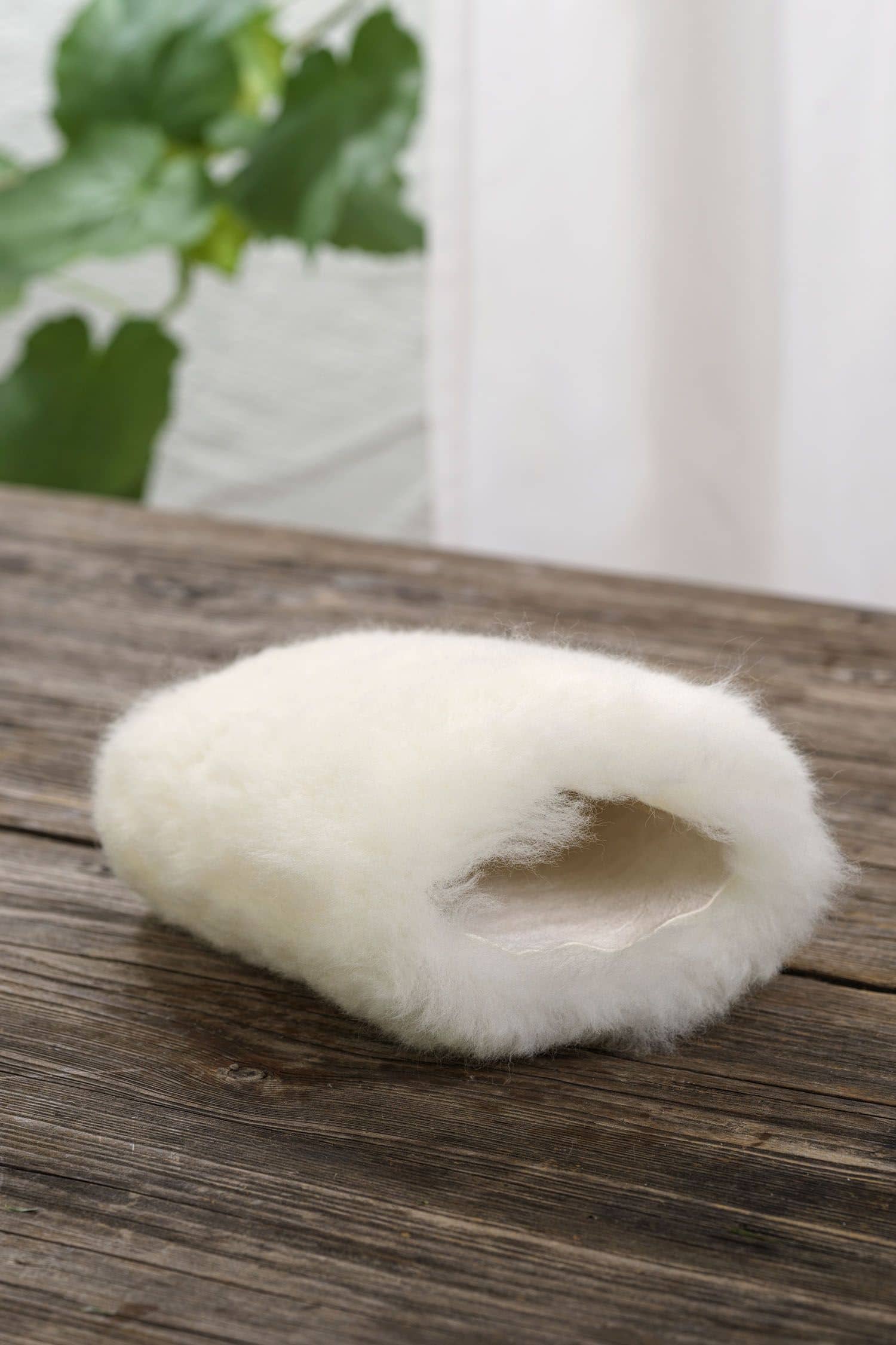 naturweißer Staubhandschuh vom Finkhof aus pflanzlich gegerbtem Schaffell auf braunem Holzboden