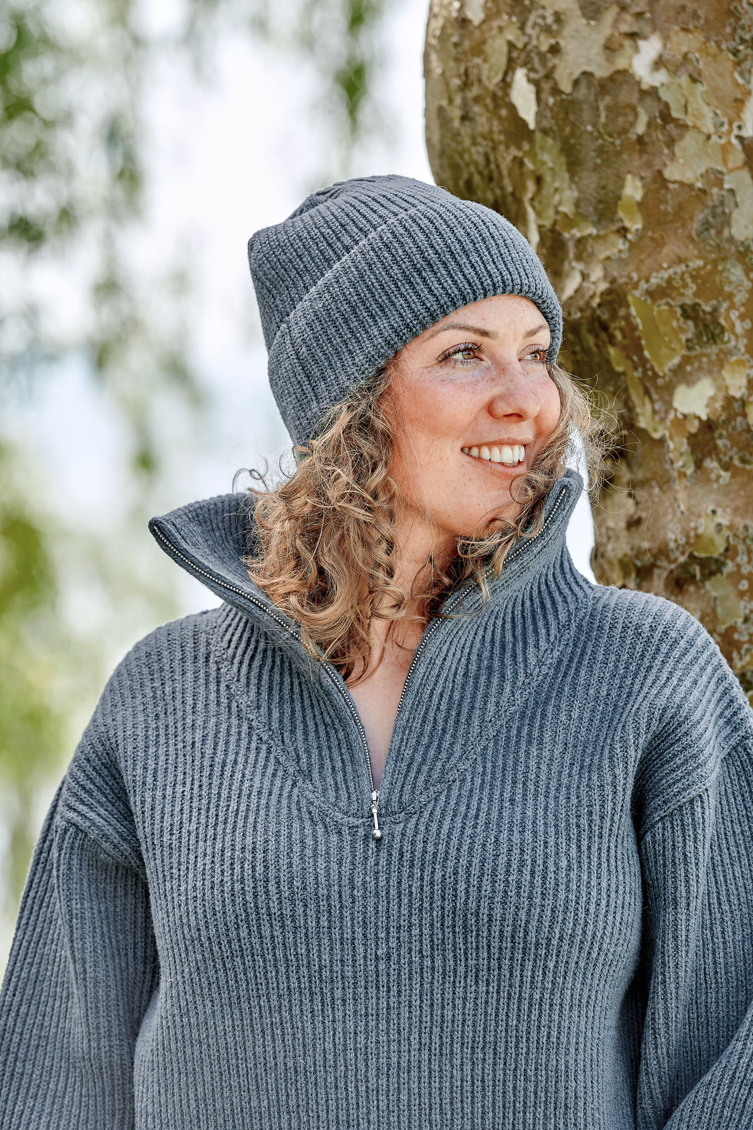 Frau trägt eine rauchblaue Finkhof Mütze aus bio Wollle (kbT) und einen Troyer