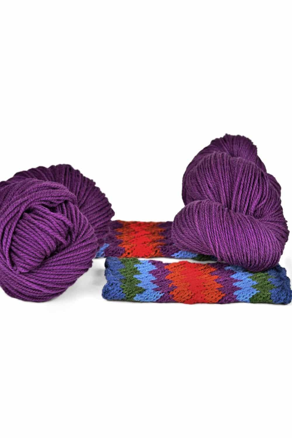 dicke lilafarbene Finkhof Merinowolle aus bio Wolle (kbT) mit Strickstück davor, weißer Untergrund