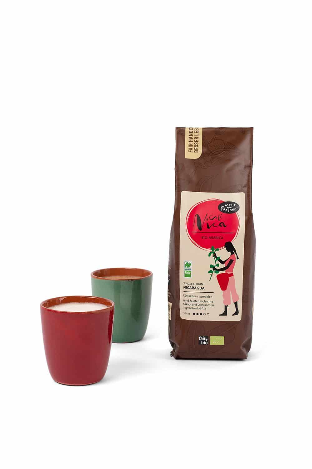 Cafe Nicaragua 500 g Nicaragua Kaffee von WeltPartner in brauner 500g Packung neben rotem und blauem Kaffeebecher