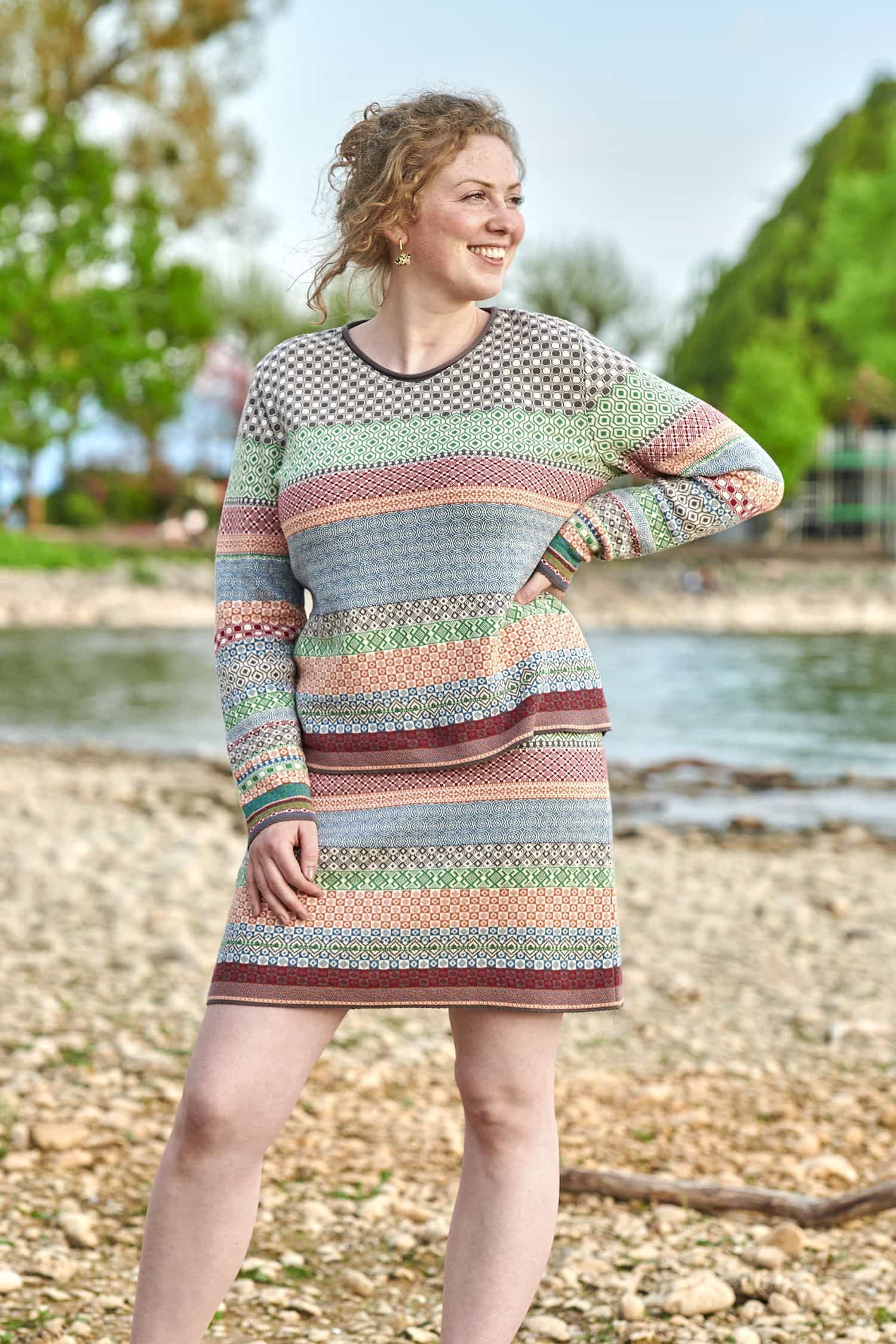 Frau trägt einen gemusterten Rock und Strickpullover aus bio Baumwolle (kbA)