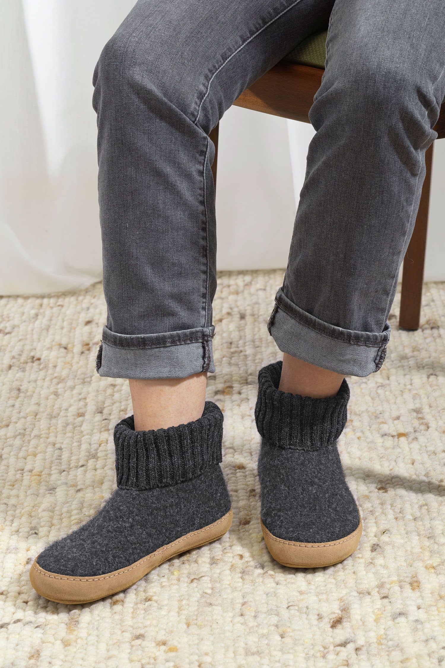 Person trägt anthrazitfarbene Finkhof Hüttenschuhe aus bio Wolle (kbT) mit einer Sohle aus pflanzlich gegerbtem Rindsleder
