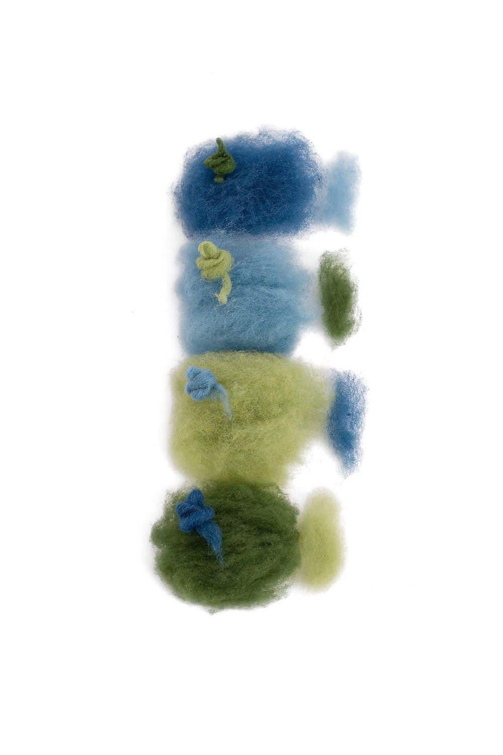 lose blau/grüne Filzwolle auf weißem Untergrund aus der Finkhof Märchenwollepackung aus bio Wolle (kbT)