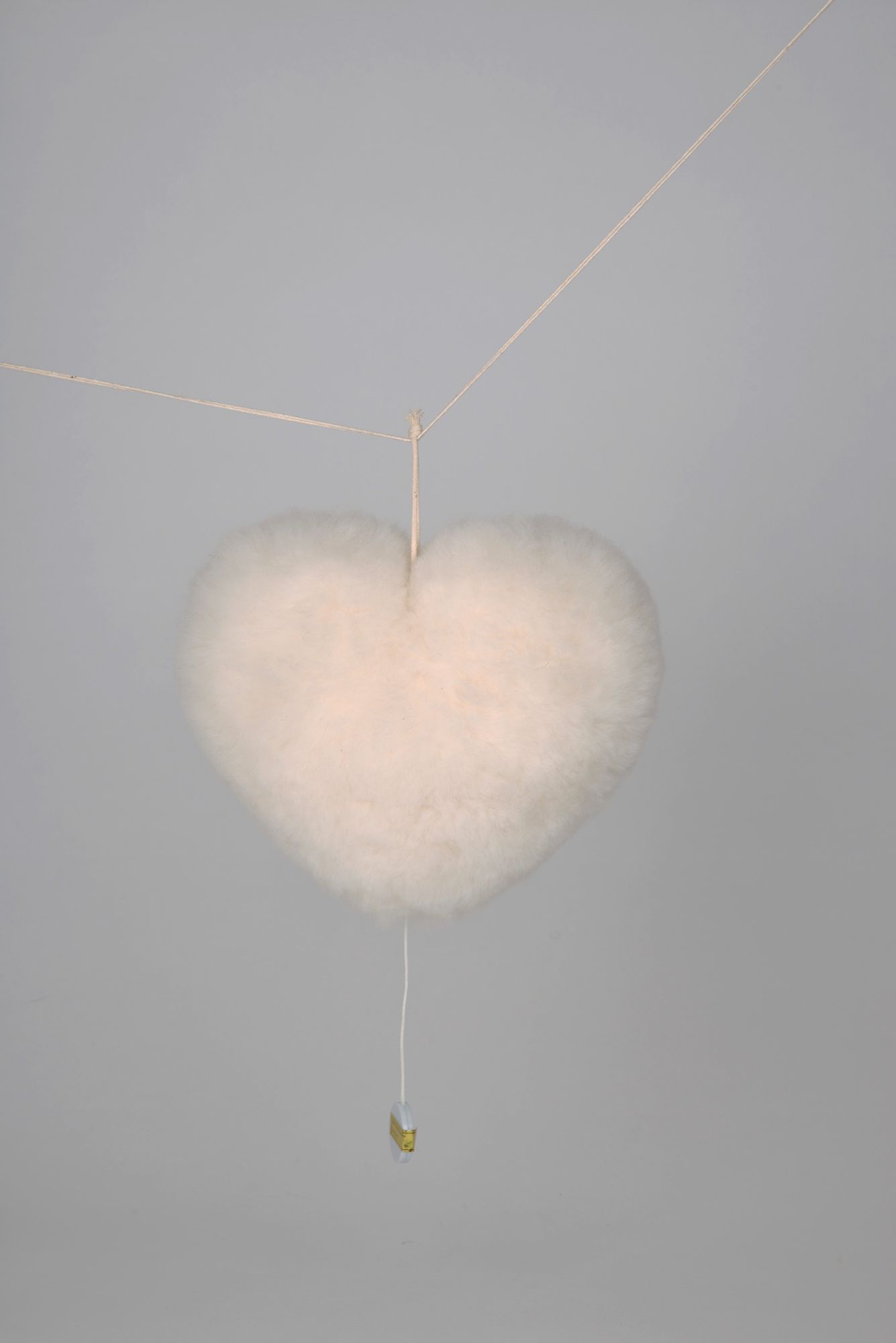 weiße Herzenspieluhr vom Finkhof aus bio Wolle (kbT) und Fell hängt auf Schnur