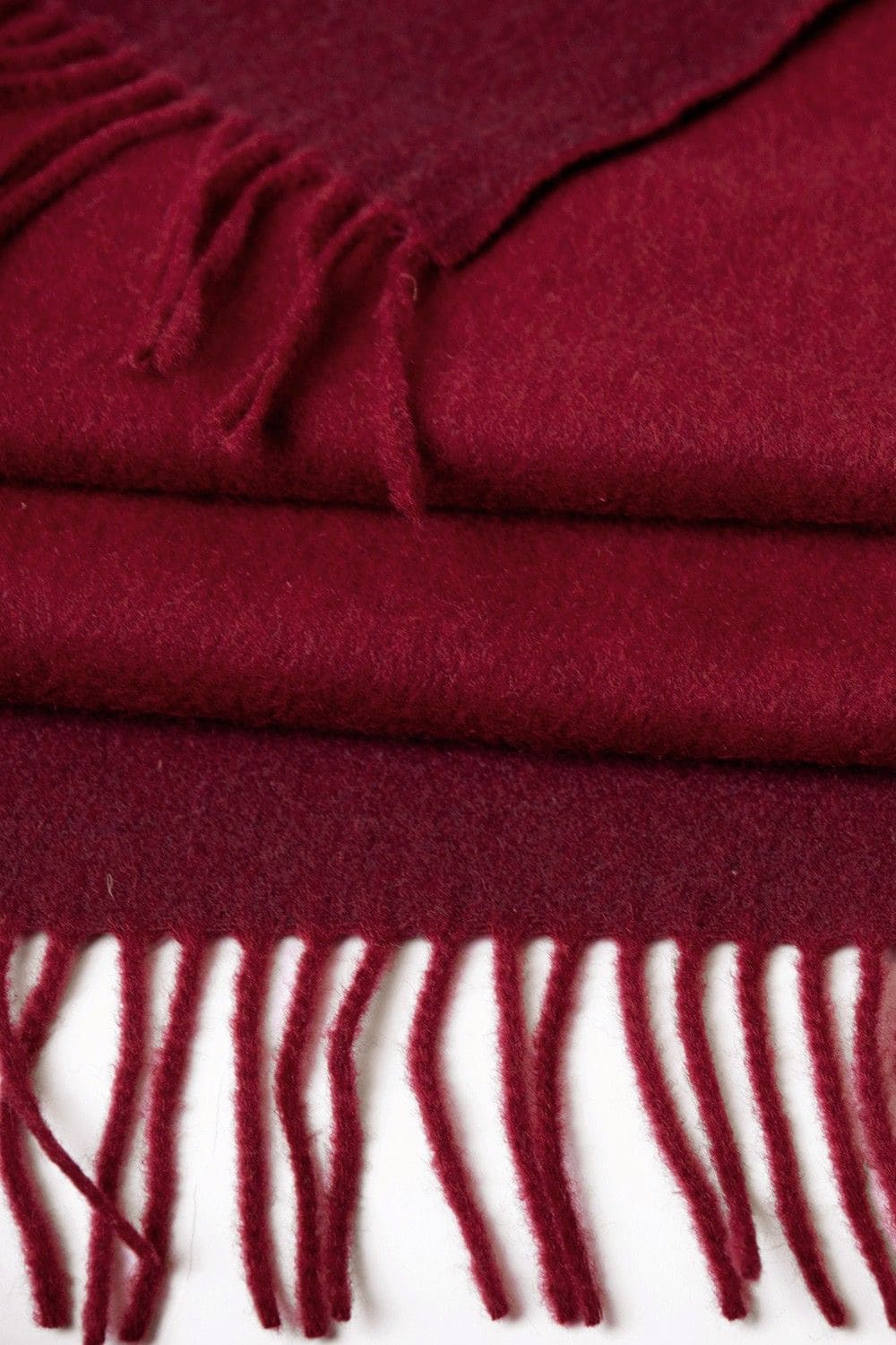 Nahaufnahme von rotem Reiseplaid mit Fransen aus bio Wolle (kbT)